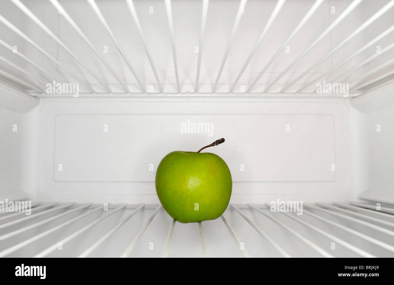Single apple sitting on shelf inside refrigerator Stock Photo