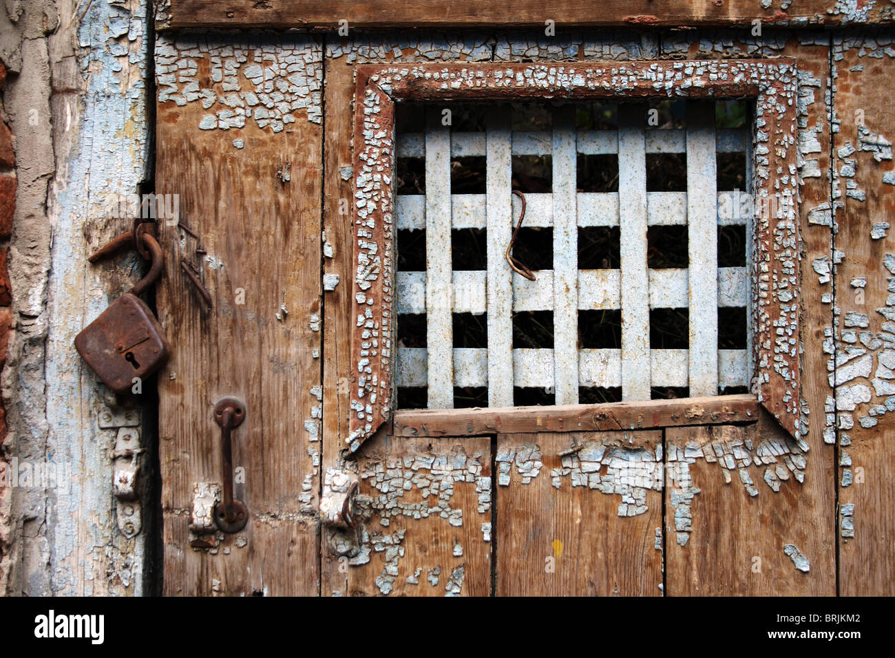 Old Weathered Wooden Door With Bars On The Window Stock Photo