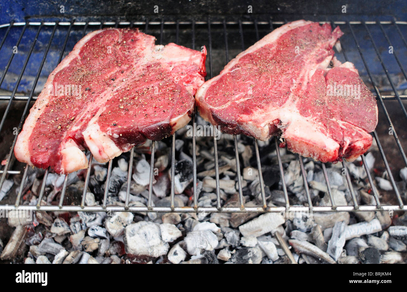 Uncooked T-bone steaks on barbecue grill Stock Photo