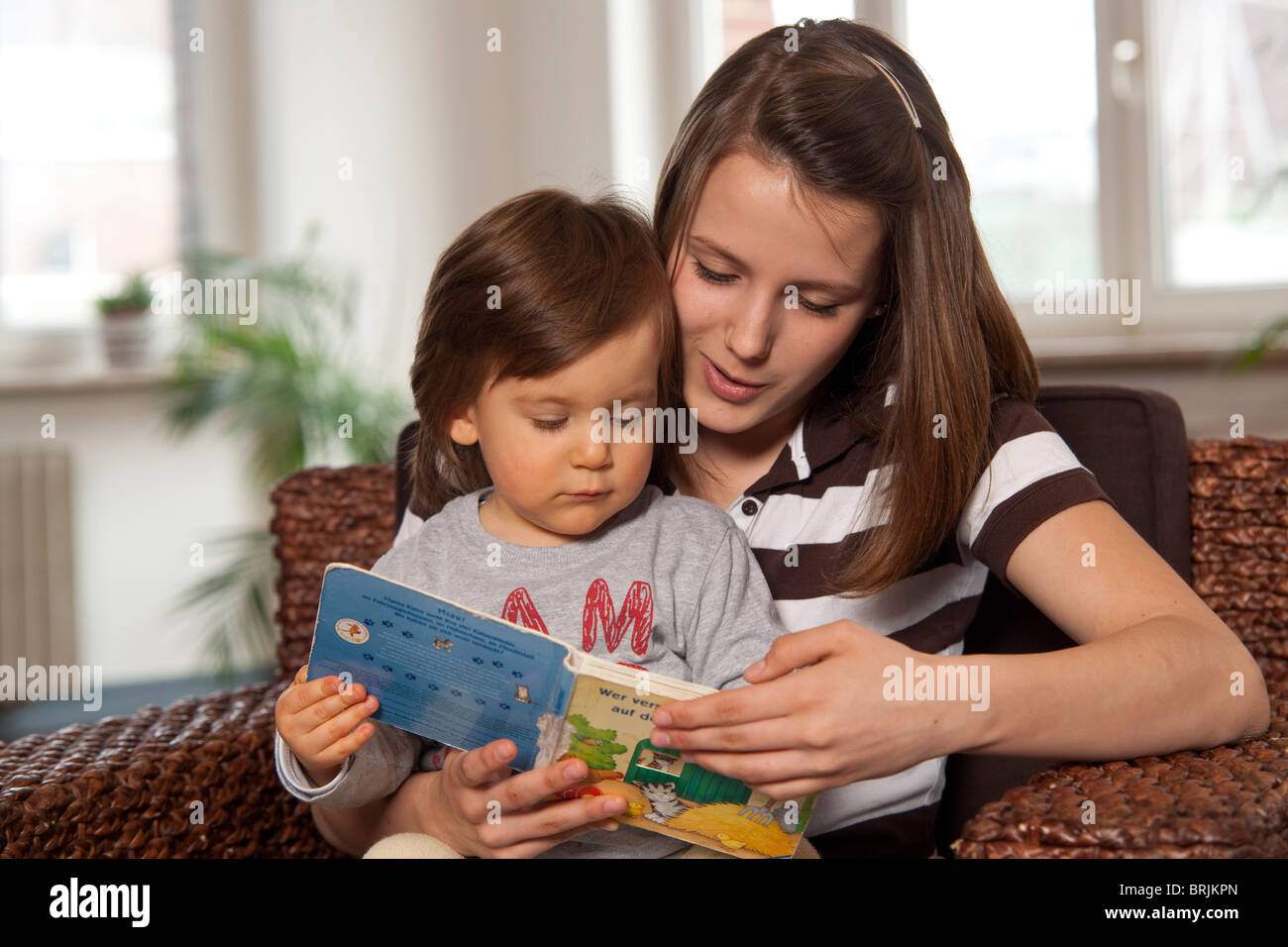 Teenage Girl Reading Book to Little Boy Stock Photo