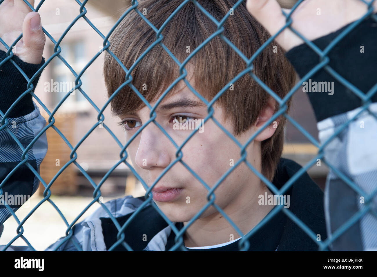 Close-Up of Teenage Boy Behind Fence Stock Photo