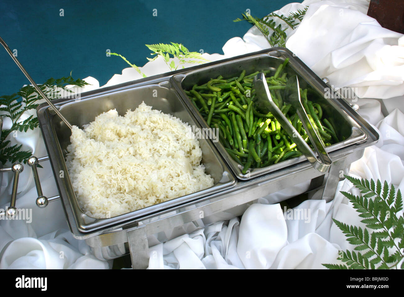 Food ready to serve in a buffet line. White rice and green beans Stock