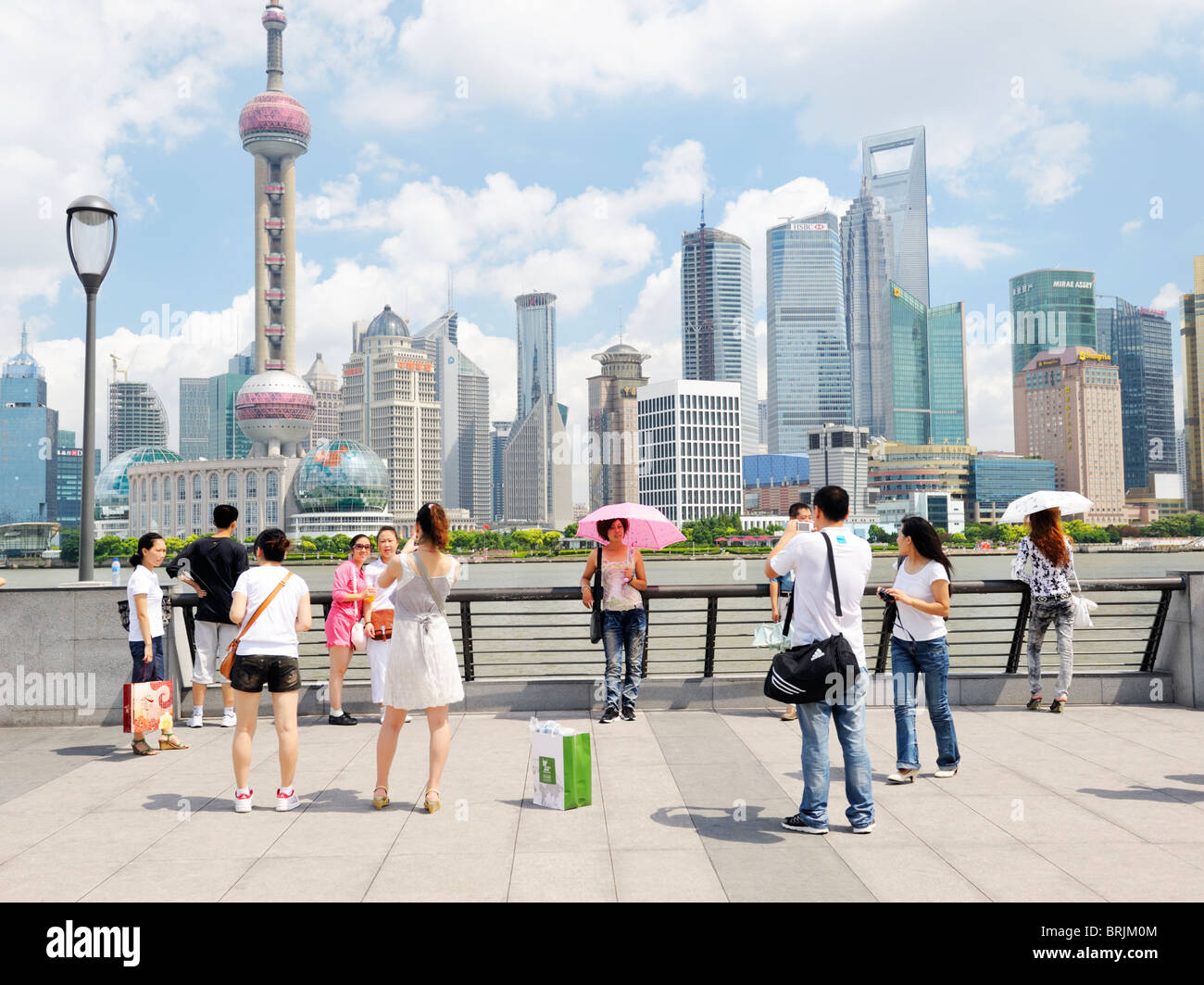 The Bund, Shanghai, China. Chinese tourists photograph each other on The Bund against backdrop of Pudong district tower skyline Stock Photo