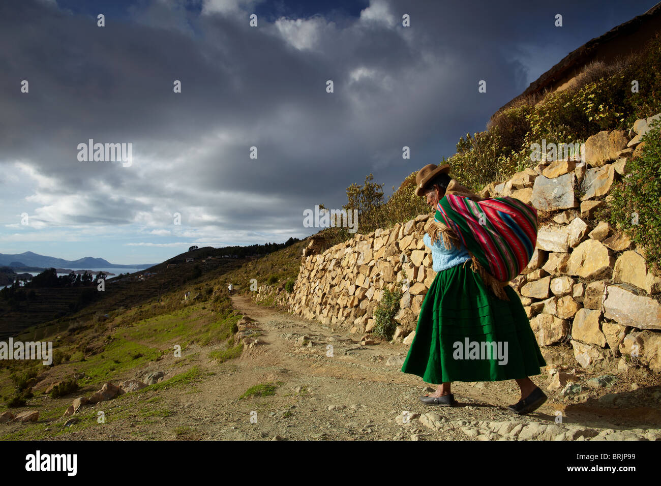 a woman with load on her back, Isla del Sol, Lake Titicaca, Bolivia Stock Photo