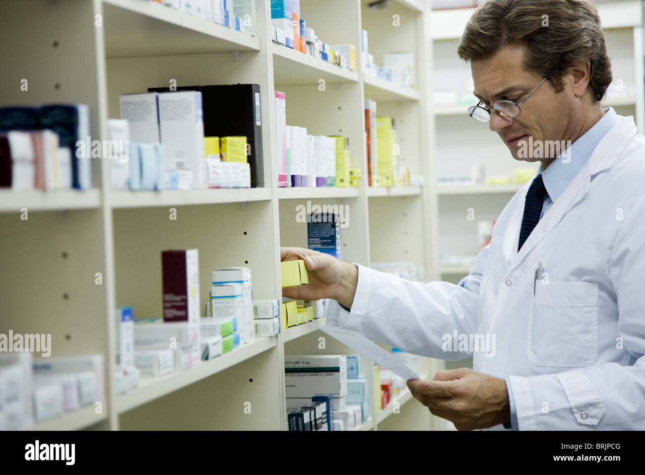 Pharmacist checking shelf for medication Stock Photo