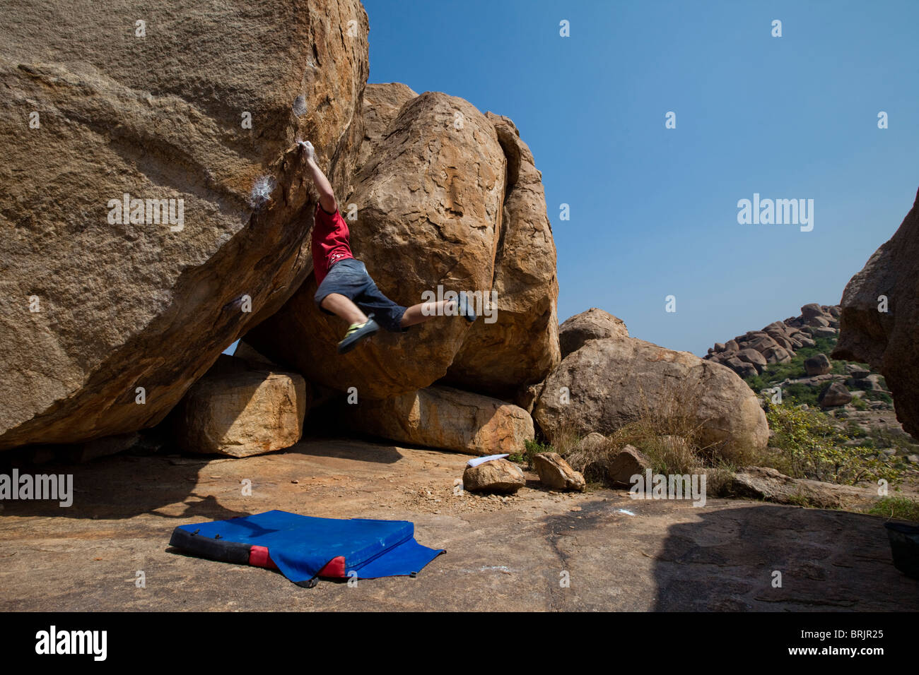 Caucasian male climber cutting loose on a highball boulder in Hampi, India. Stock Photo