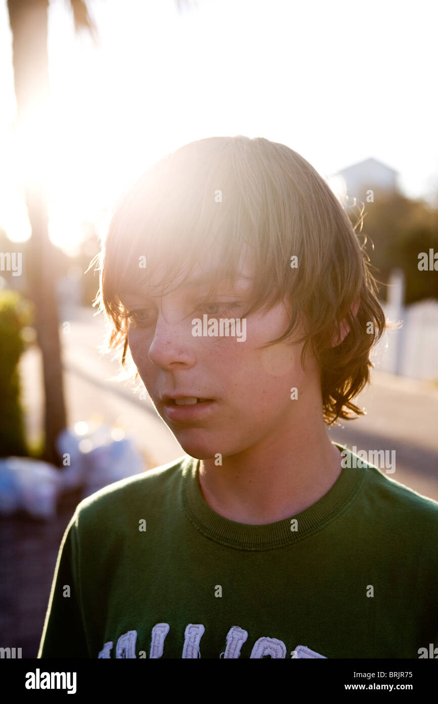 A teen boy is staring with the sun shining behind him. Stock Photo