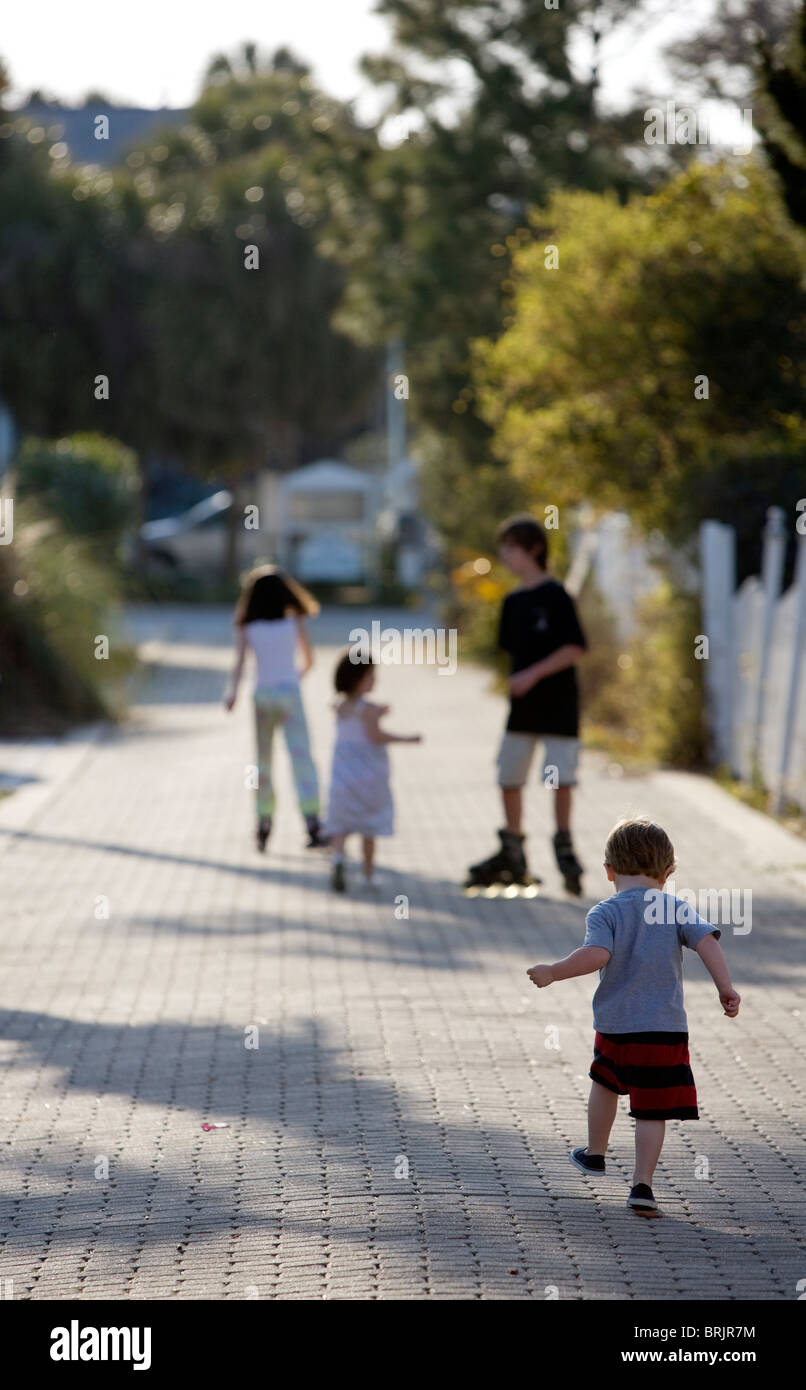 A group of kids are roller blading and walking down an alley. Stock Photo
