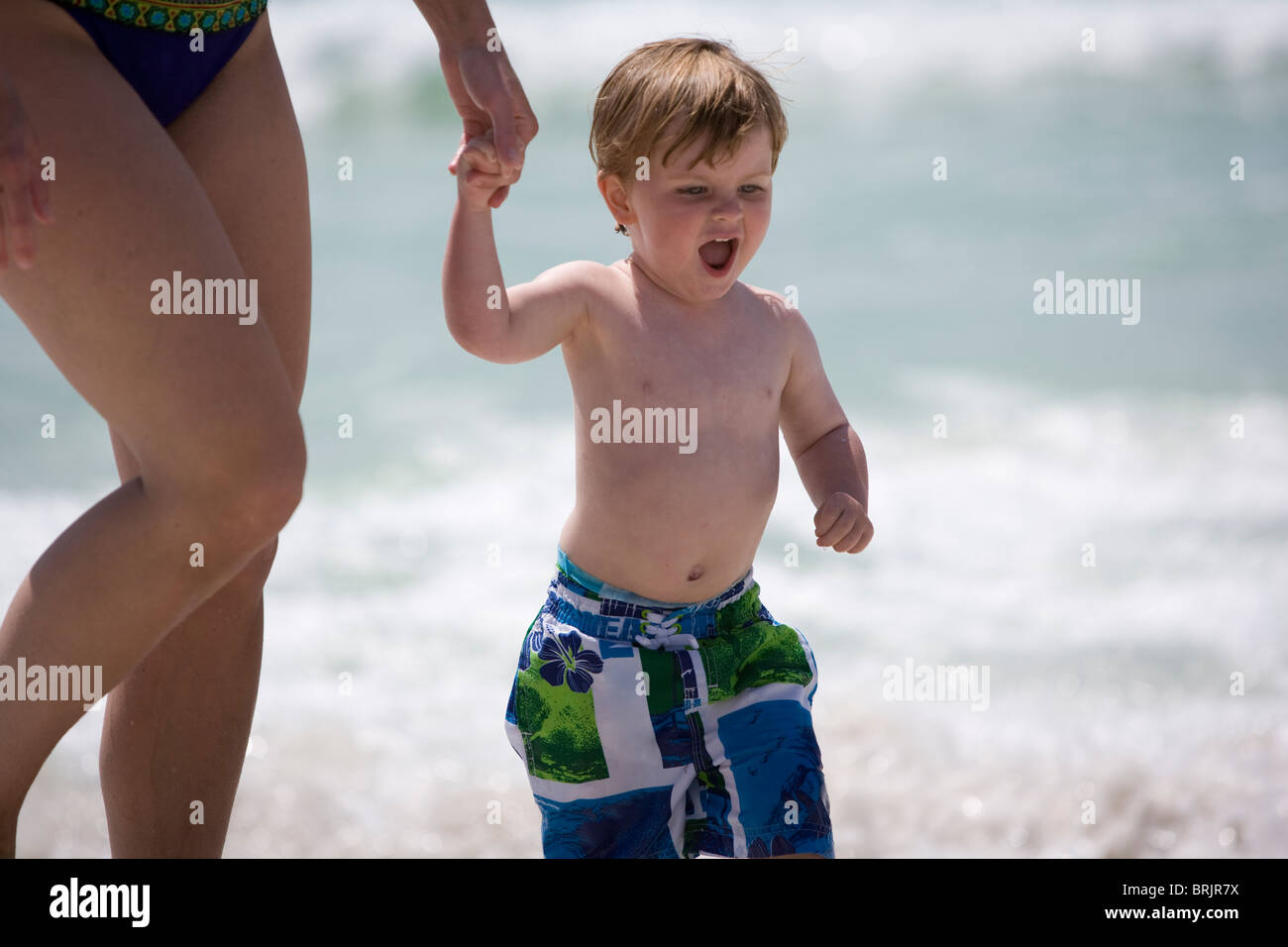 A boy and mom are holding hands at the beach. Stock Photo