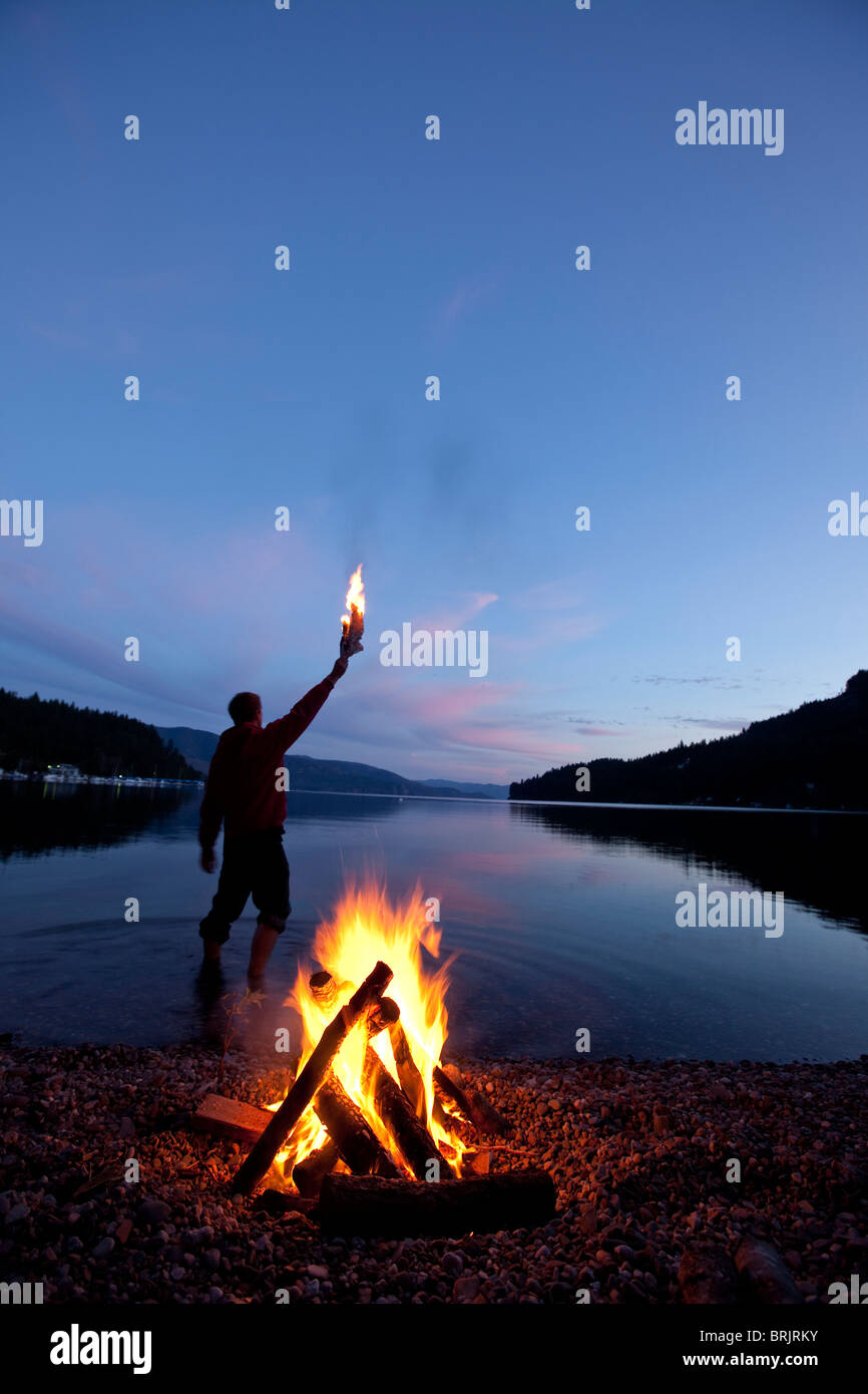 Lone figure stands behind campfire in Idaho. Stock Photo
