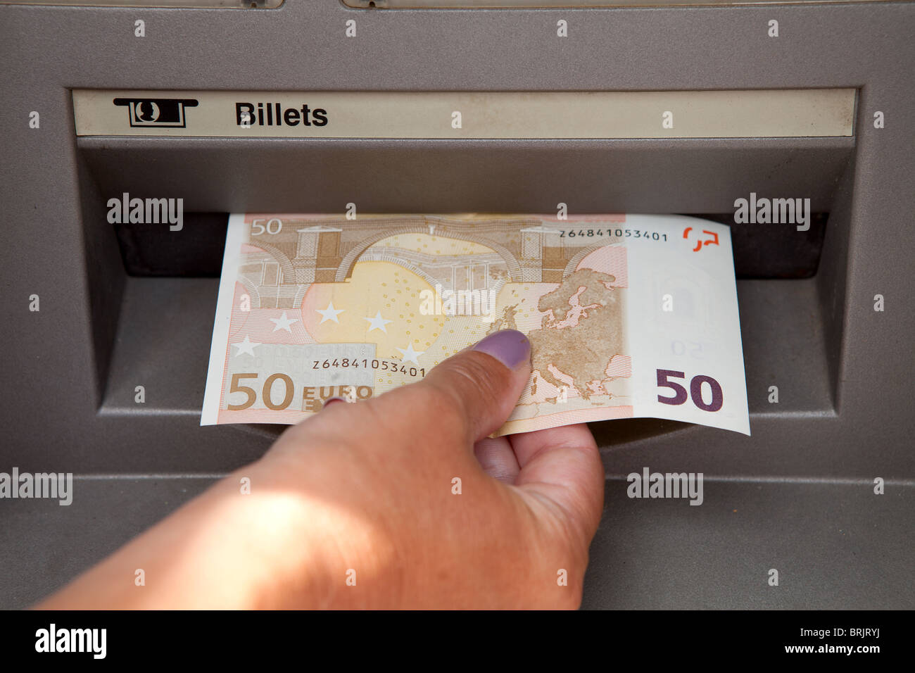 ATM Access : a womans hand withdraws money at cashpoints Stock Photo