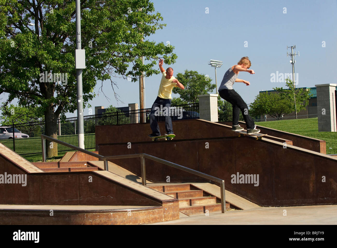 Two skateboarders grinding a rail at a skate park Stock Photo Alamy