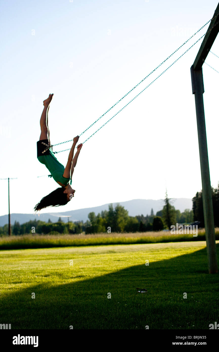 A young women swinging smiles while looking back on a summer evening in Idaho. Stock Photo