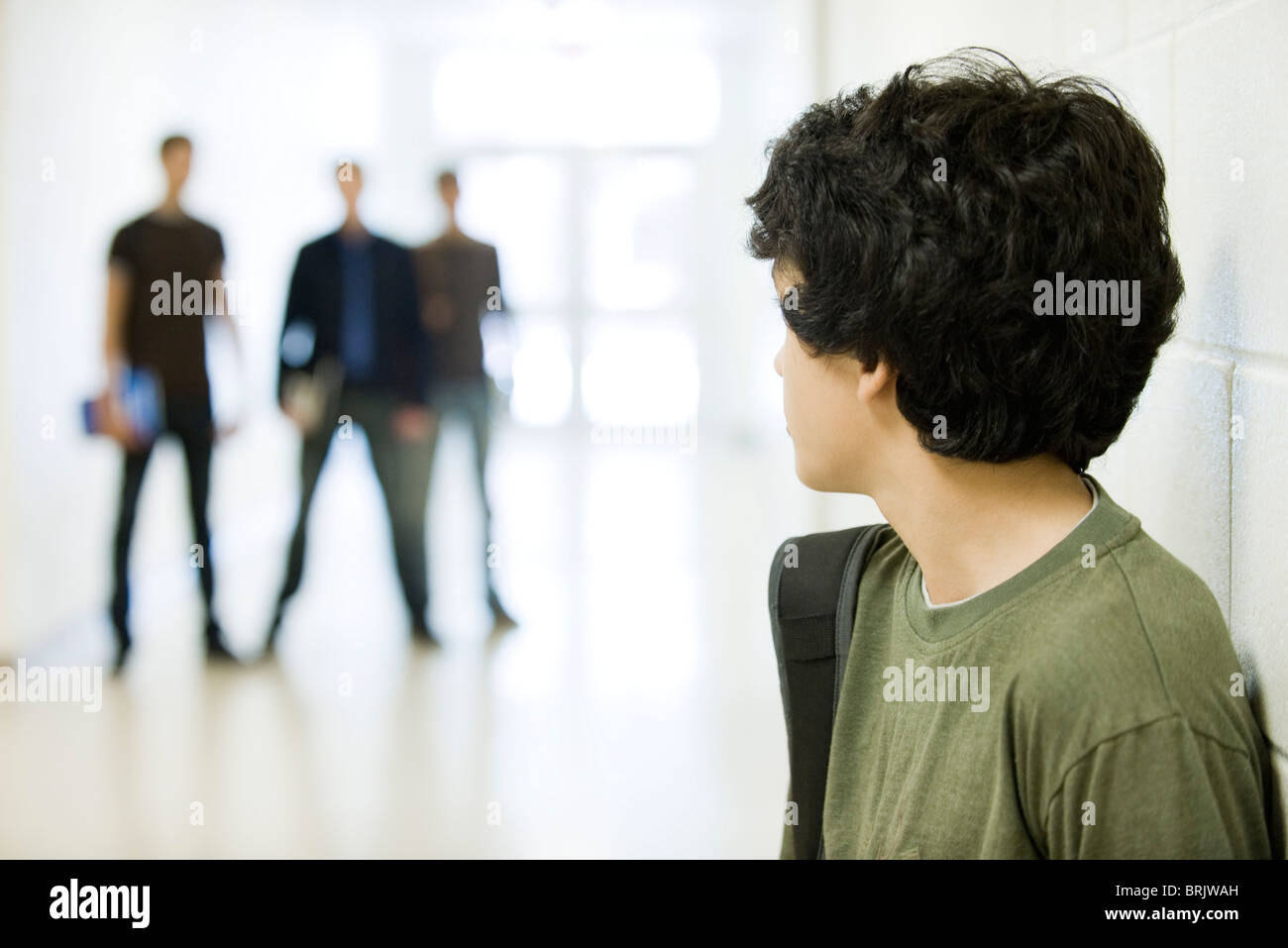Teenage boy looking over shoulder at bullies in background Stock Photo