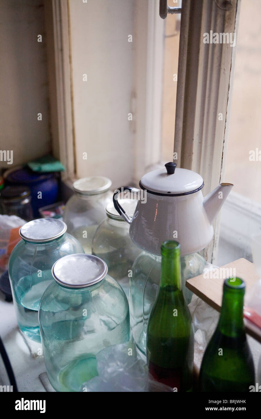 Preserving jars with aluminium lids, bottles and enamel teapot in old Soviet apartment St Petersburg Russia Stock Photo