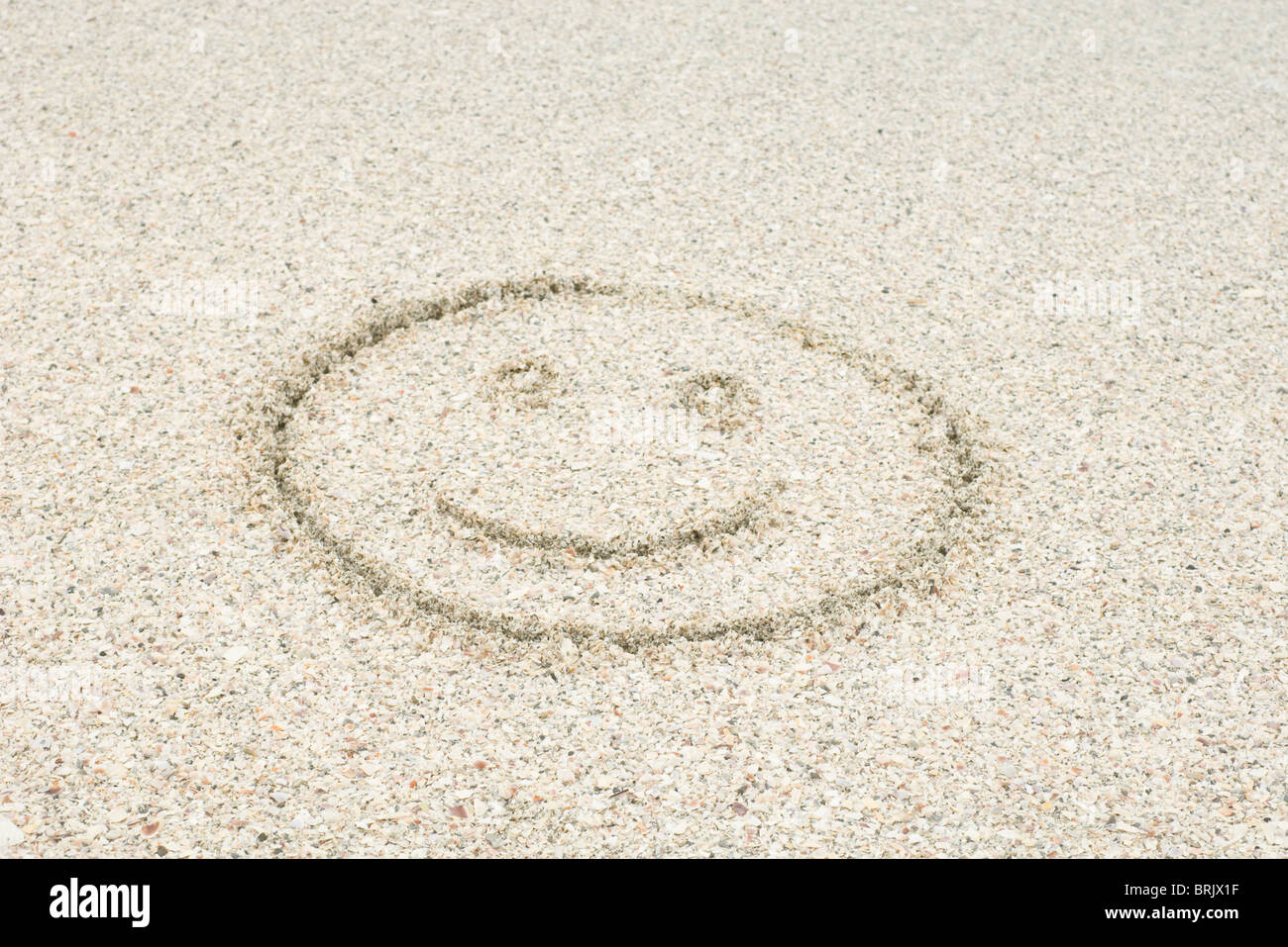 Smiley face drawn in sand at the beach Stock Photo