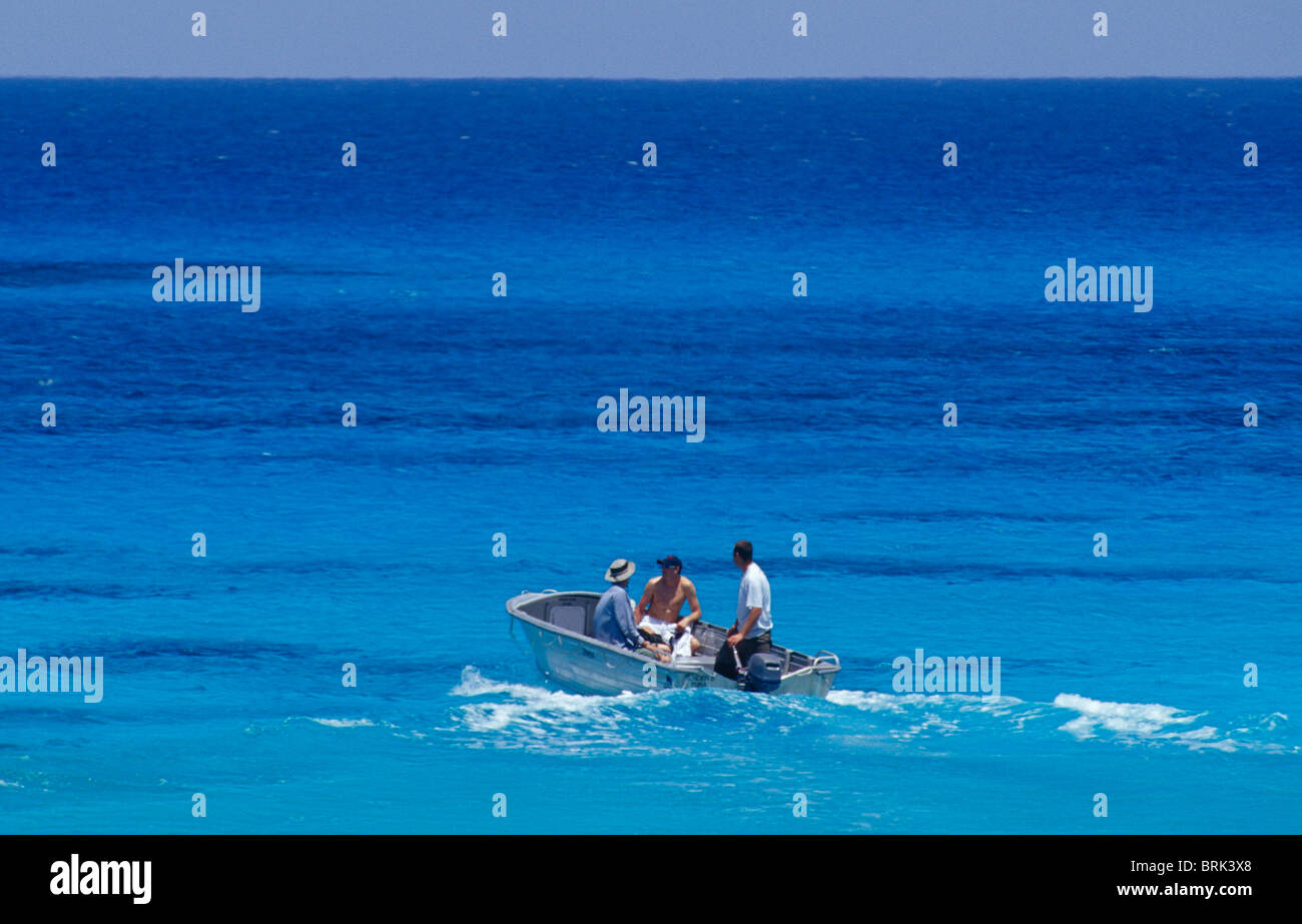A group of men on a tropical turquoise ocean in an aluminium dingy