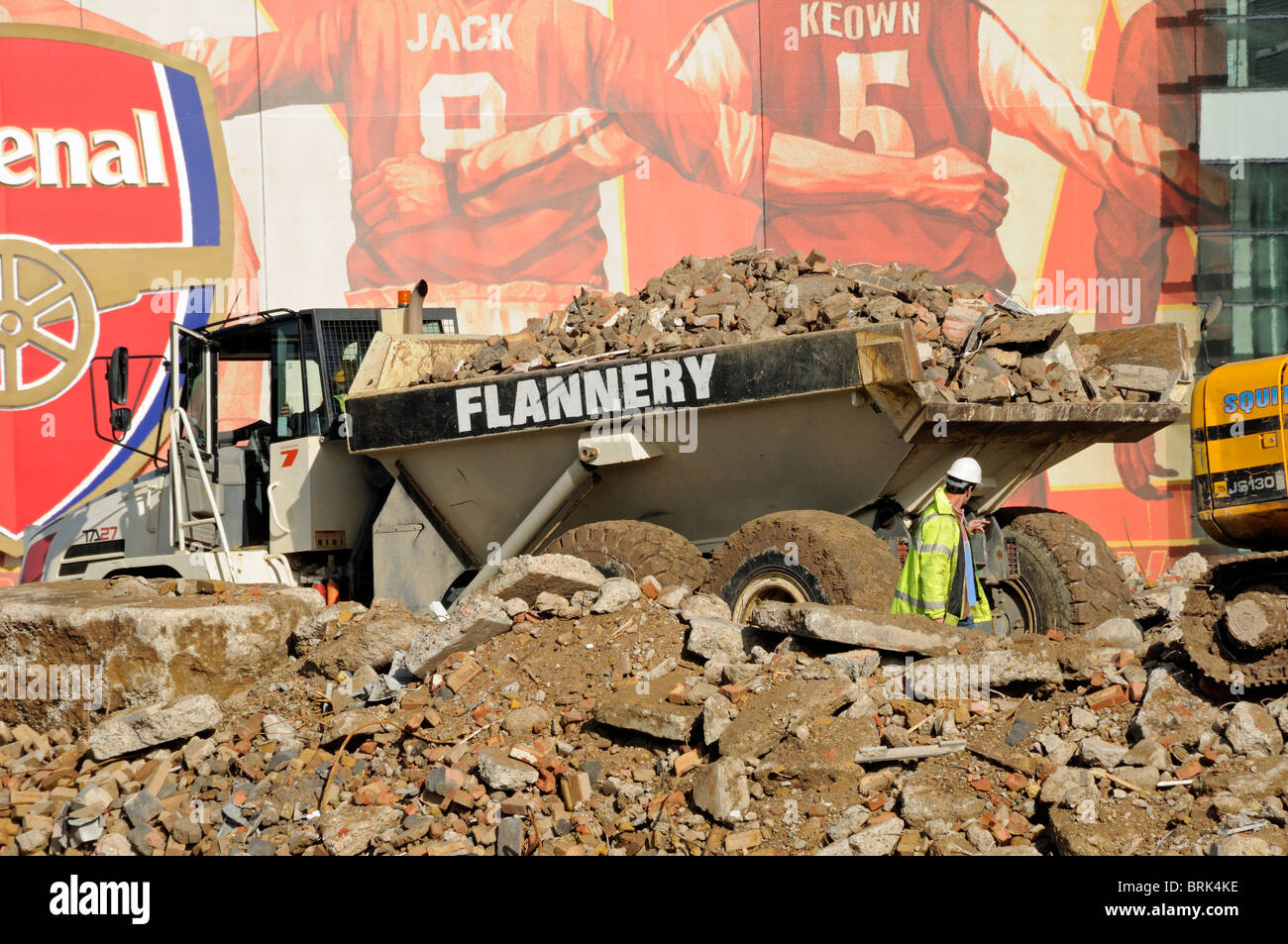 Man directing a lorry full of rubble on demolition site in front of the Emirates Stadium Holloway London England Britain UK Stock Photo