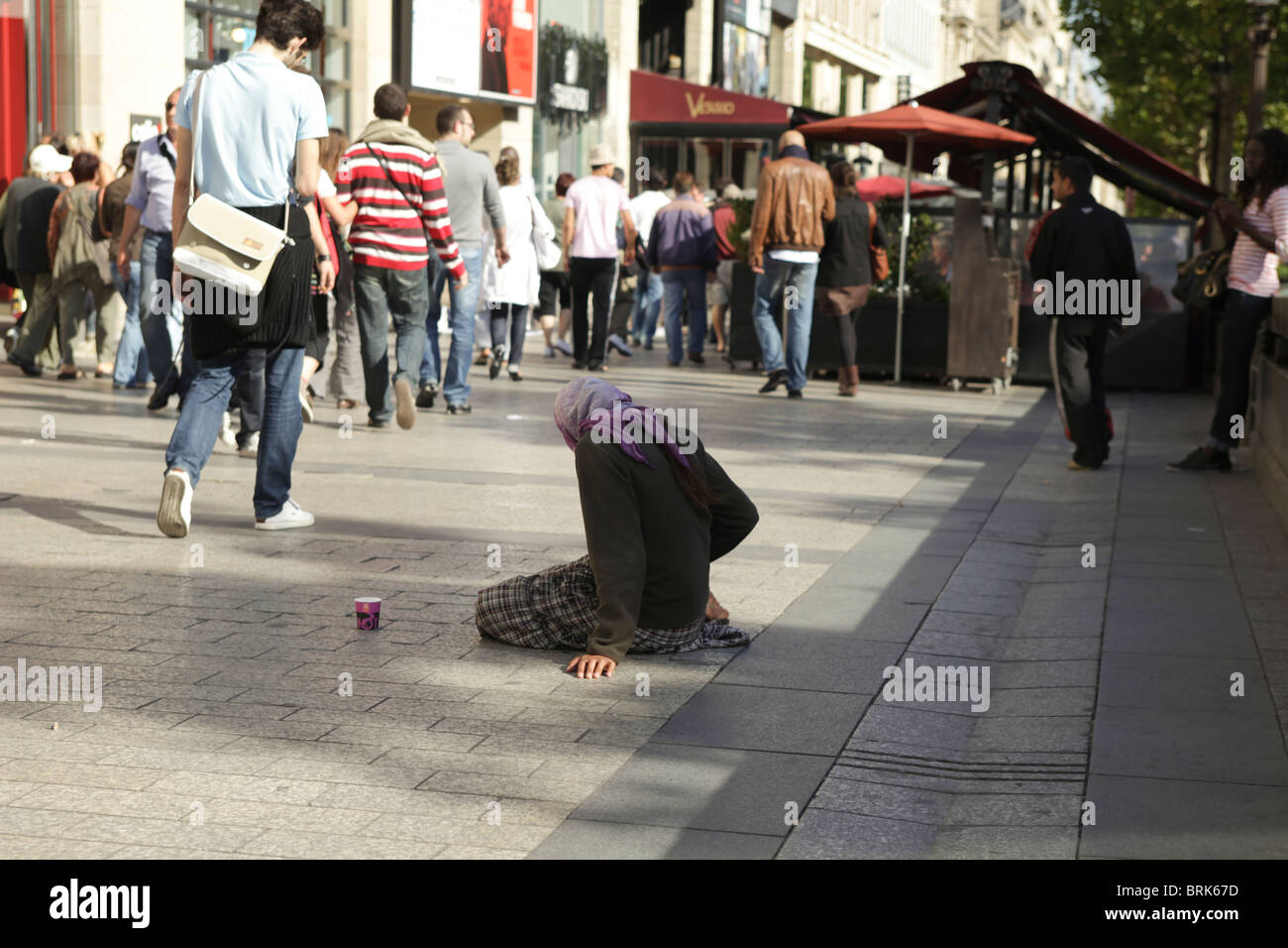 Roma woman begging on the Champs elysees in Paris Stock Photo