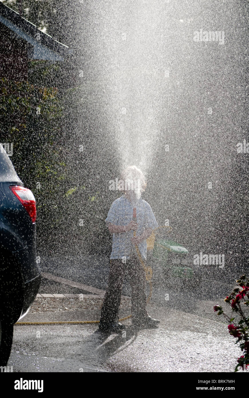Boy with hosepipe washes parent's car Stock Photo Alamy