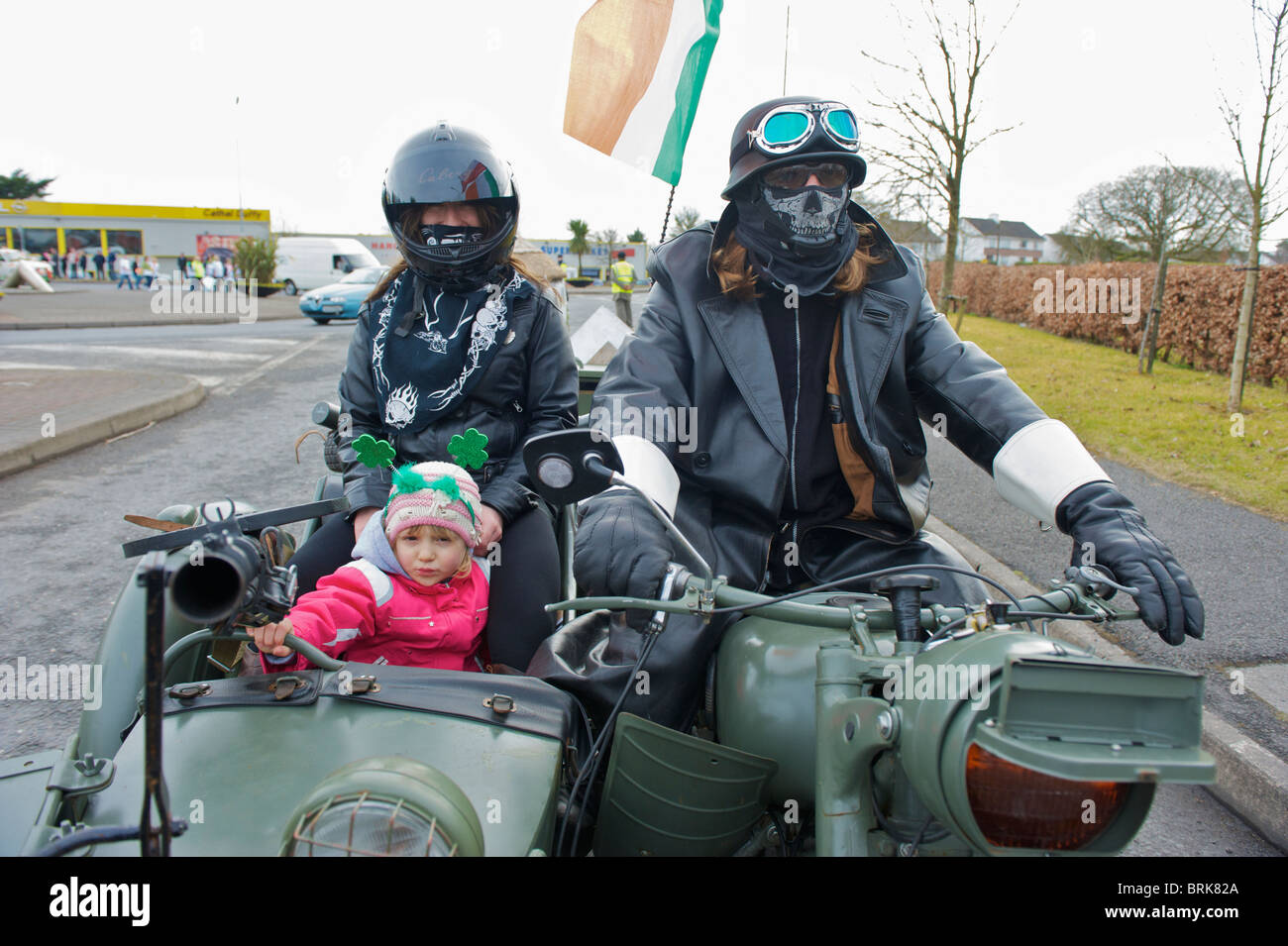 A family riding an old motorcycle and sidecar in the St. Patrick's day