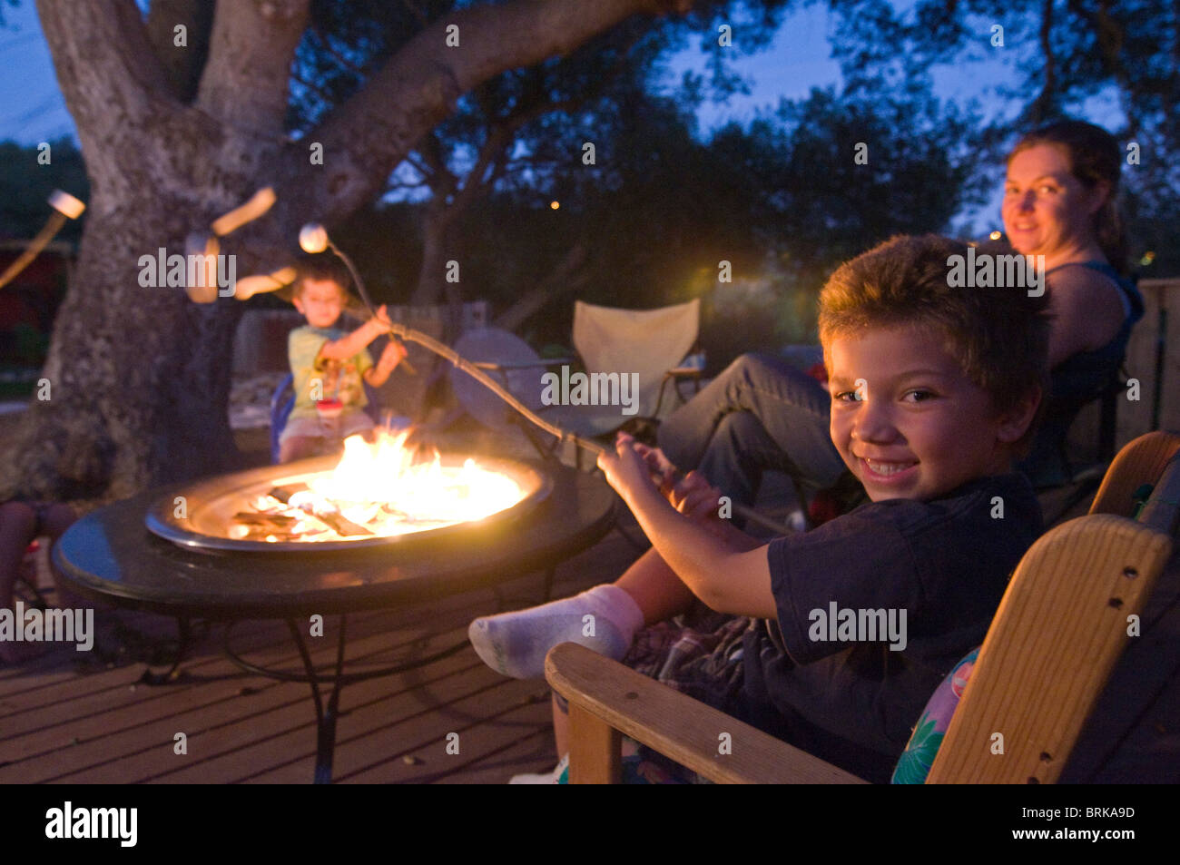 A family toasting marshmallows over a fire in their backyard Stock ...