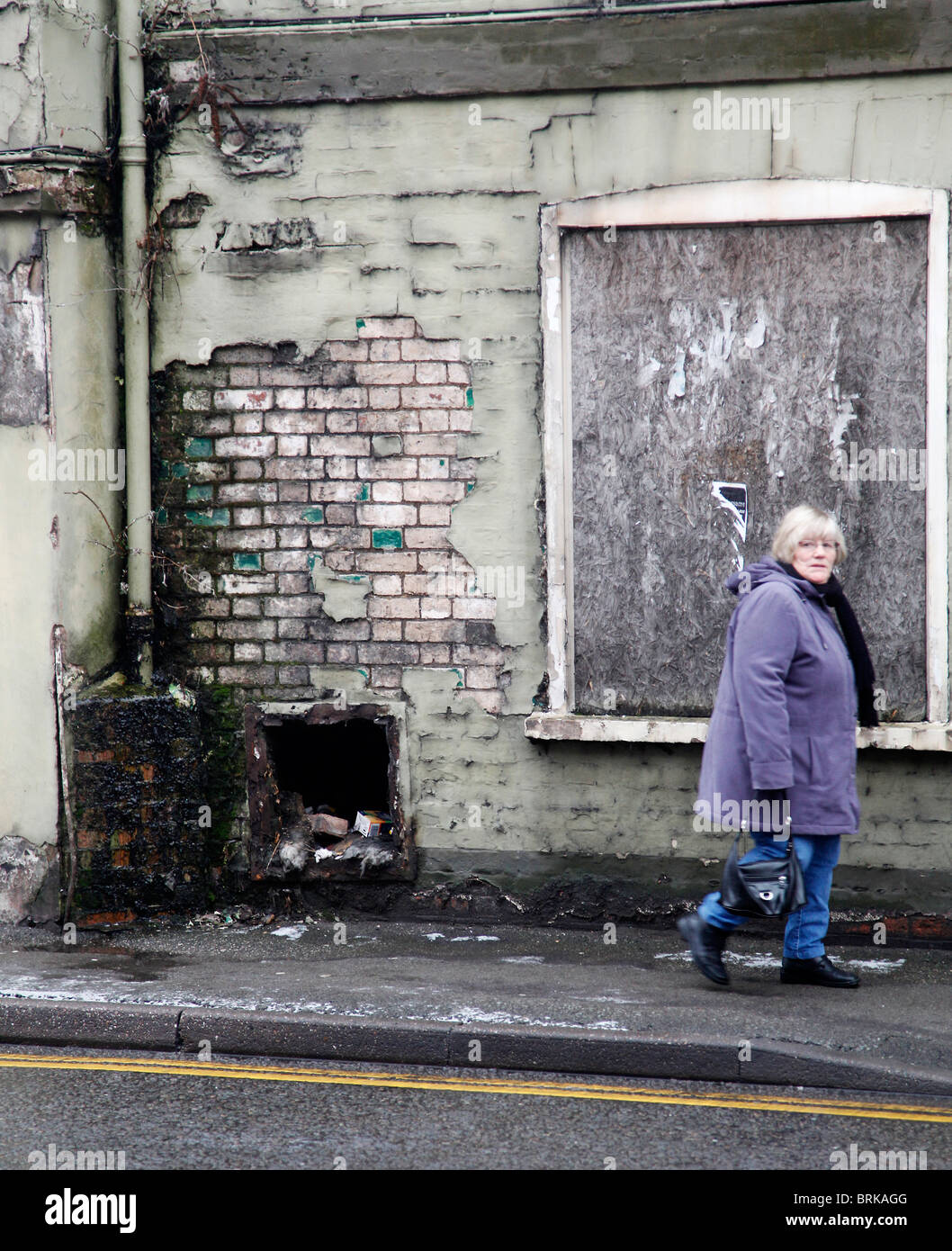 A woman walking past a derelict abandoned building Stock Photo - Alamy