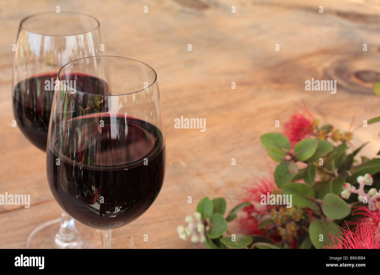 Glasses of Red Wine on Outdoor Table with Pohutukawa Stock Photo