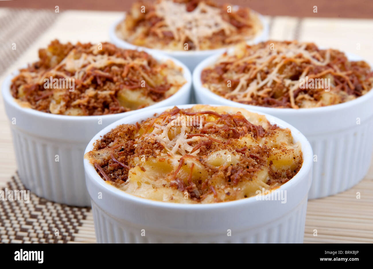 four ramekin bowls of homemade macaroni and cheese dinner topped with brown toasted cheesy crust Stock Photo