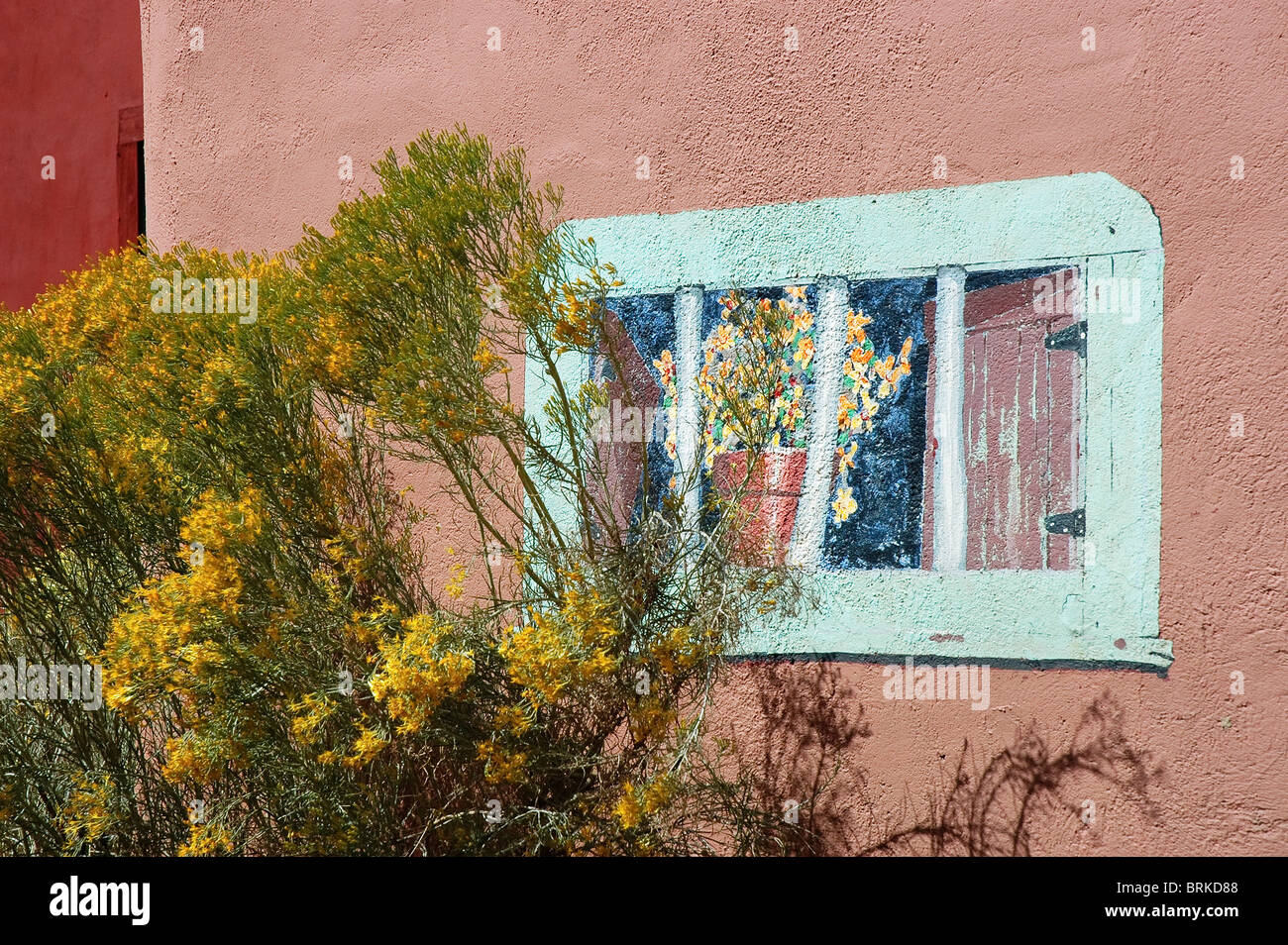 Yellow chamisa bush next to wall art, Madrid, NM., along the Turquoise Trail. Stock Photo