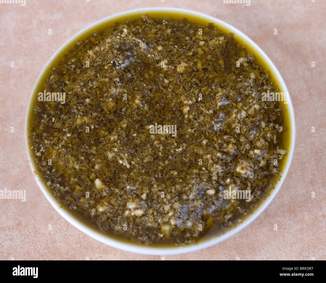 fresh homemade basil pesto sauce in a small white preparation bowl Stock Photo