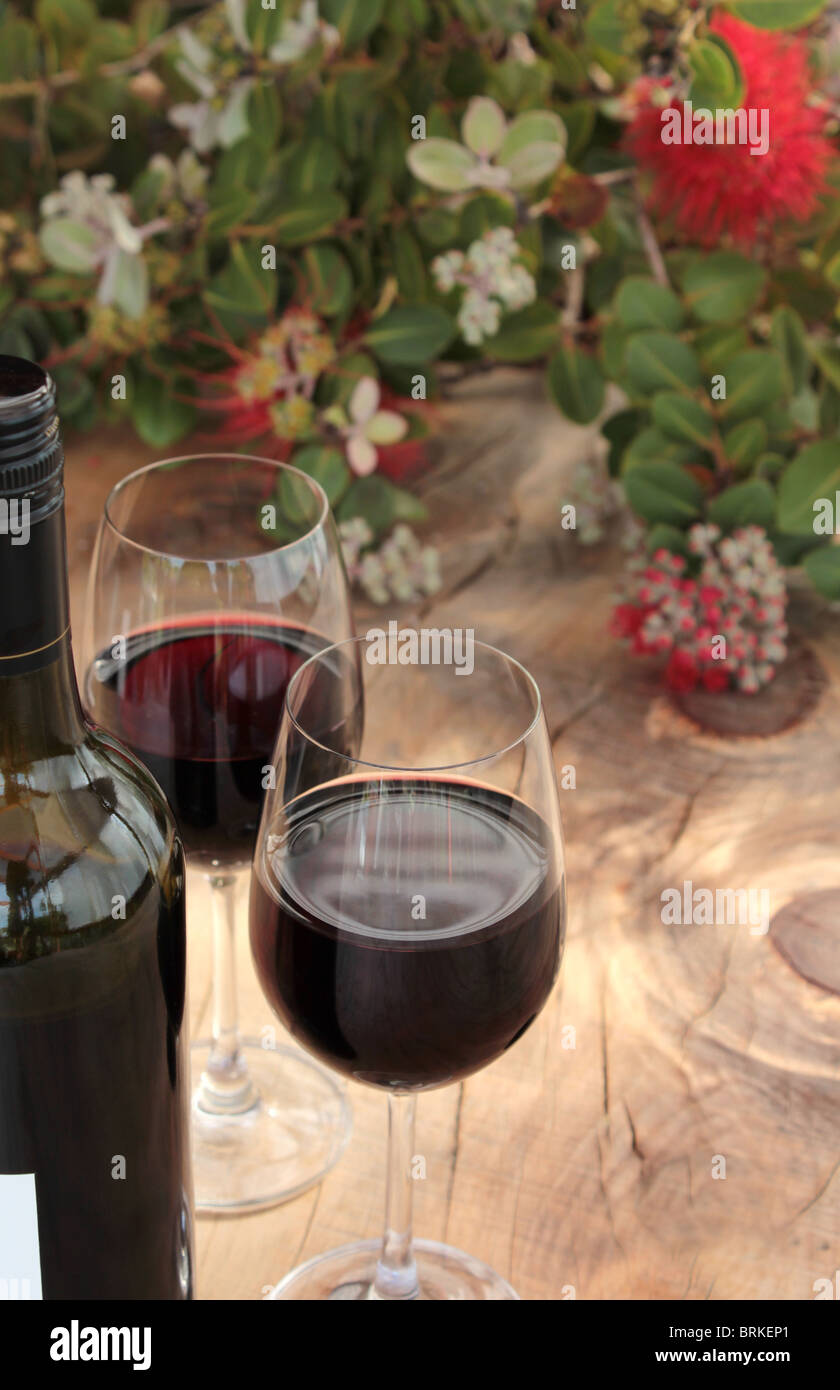 Bottle & Glasses of Red Wine on an Outdoor Wooden Table Pohutukawa Stock Photo