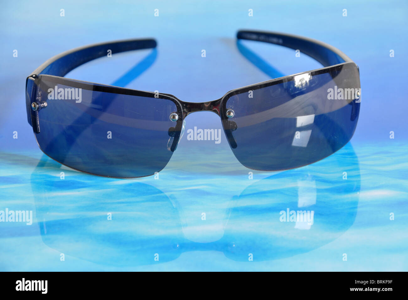 A pair of sunglasses sitting on a watery like surface. Stock Photo