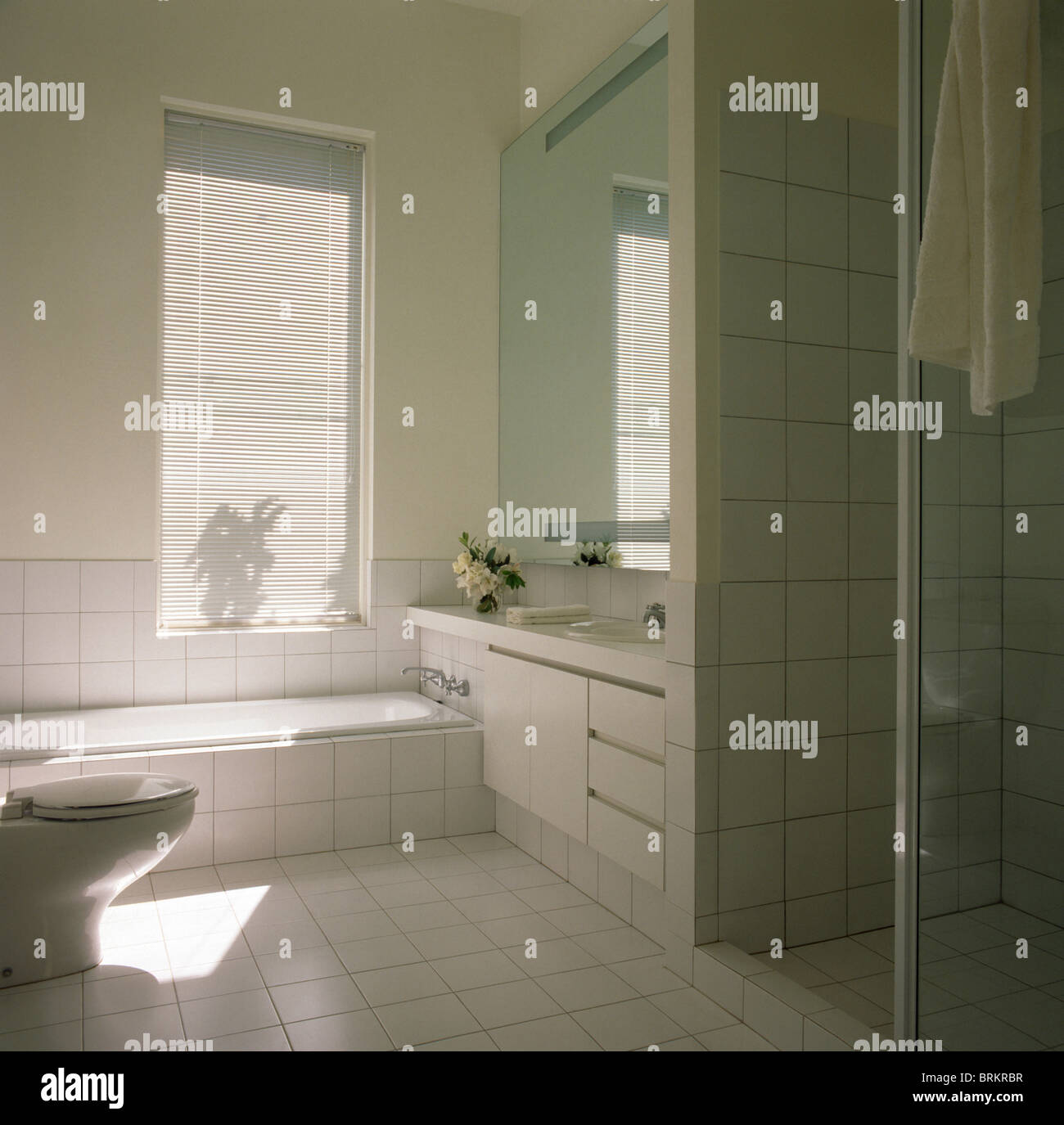Bath below window in modern white tiled bathroom Stock Photo Alamy