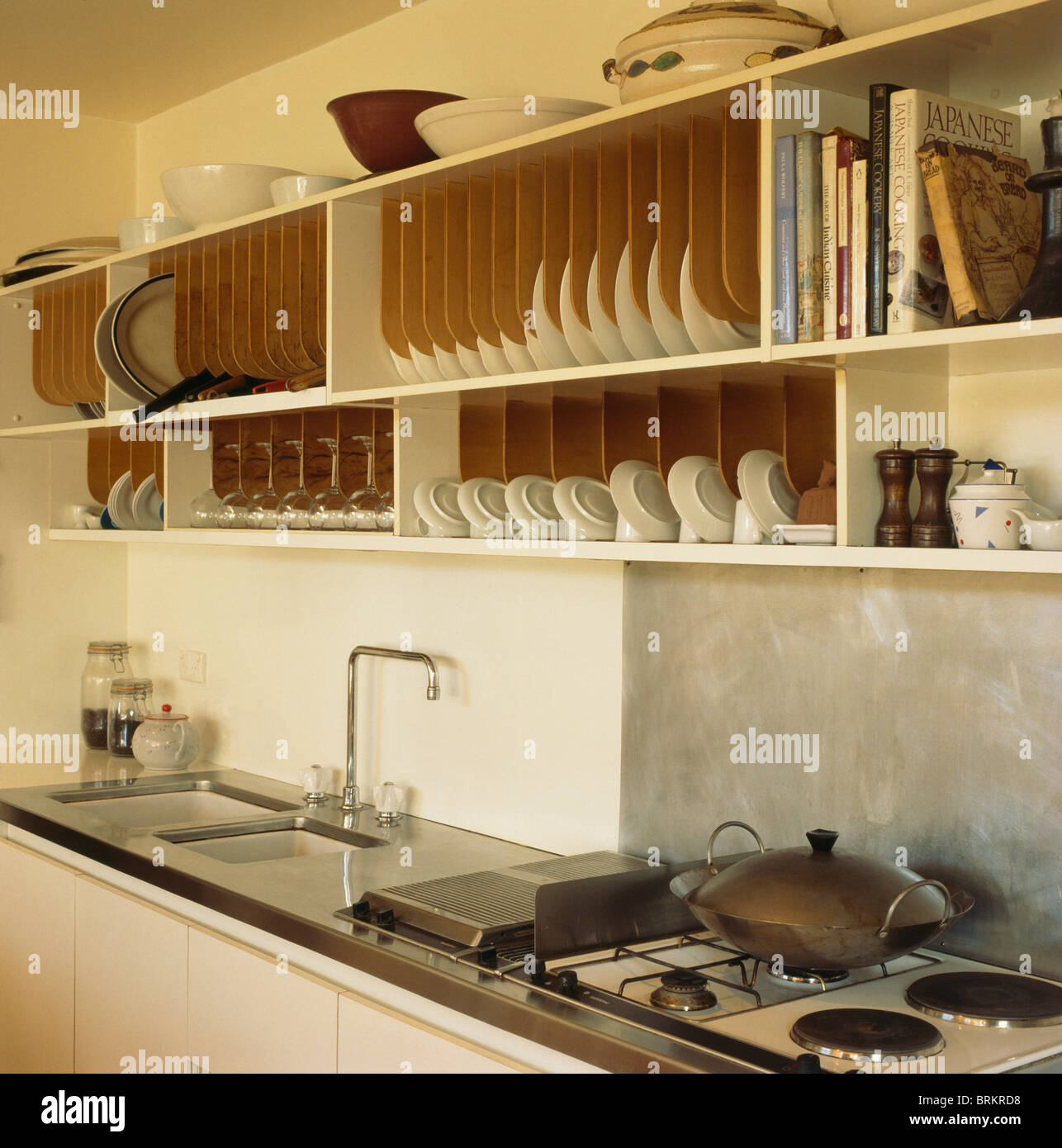 Fitted wooden plate racks in shelving above sink and gas 