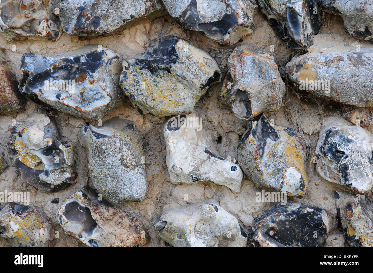 Old flint wall showing roughly knapped flints and worn mortar. West Sussex Stock Photo