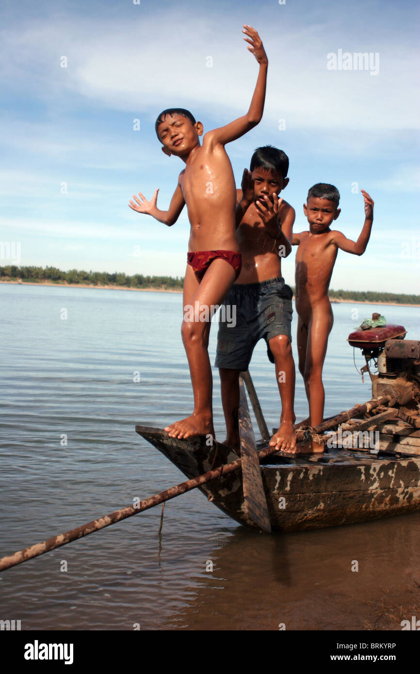 Three boys use an old wooden fishing boat as a diving platform on the