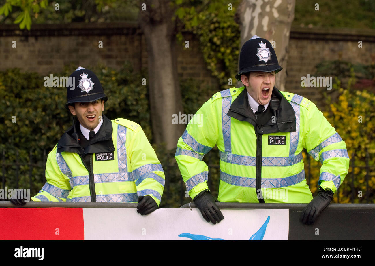 two policemen maintain a police presence at the London Marathon an annual event in yellow high visibility fluorescent jackets Stock Photo