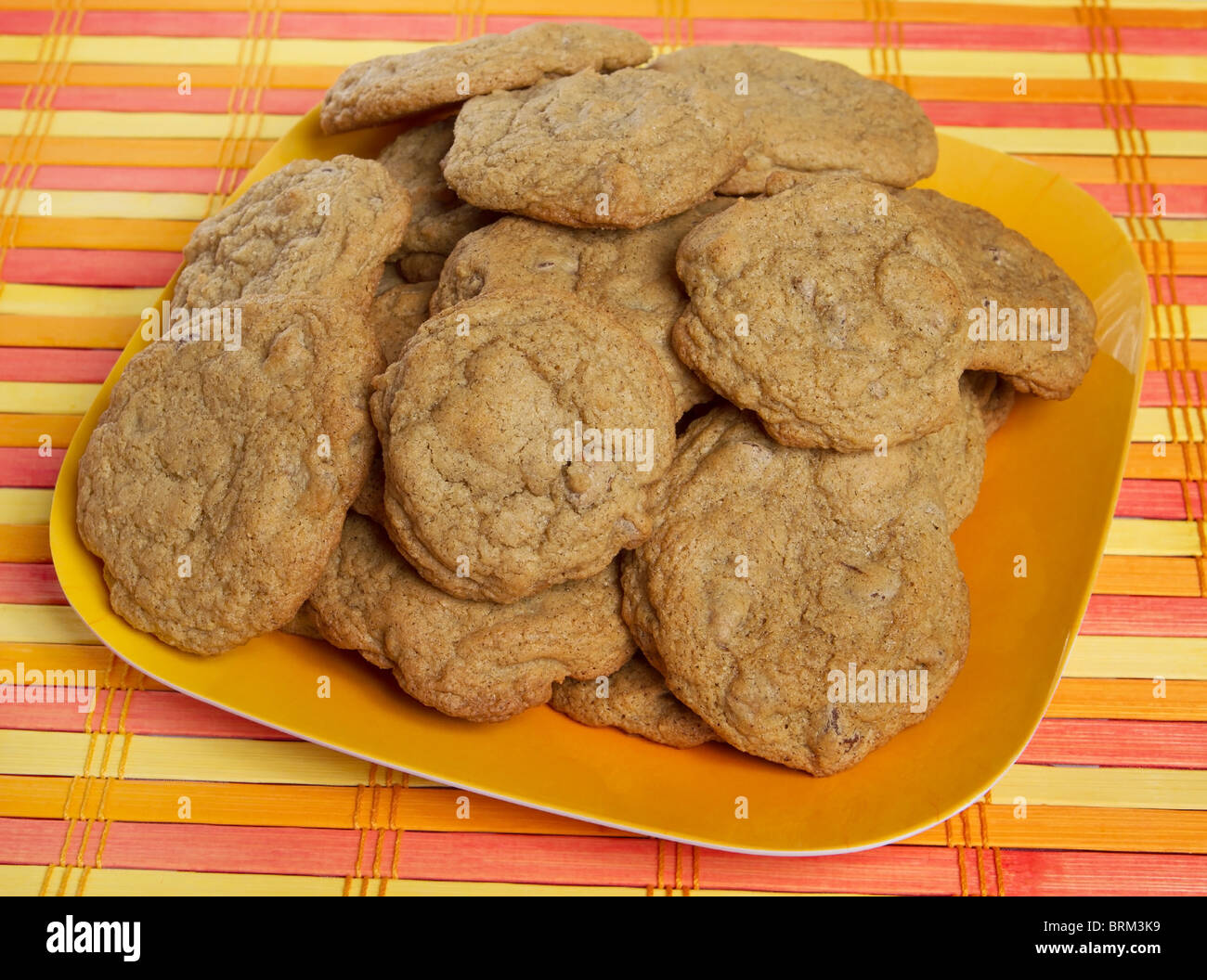 small stack of gluten free chocolate chip cookies on a yellow and orange background Stock Photo