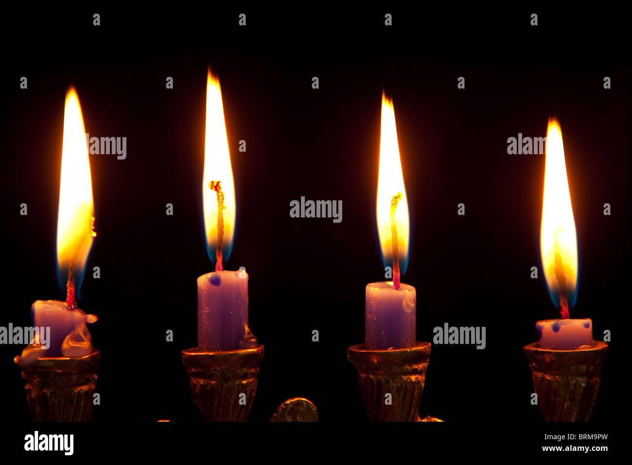 burning hanukkah candles in a menorah on black background Stock Photo