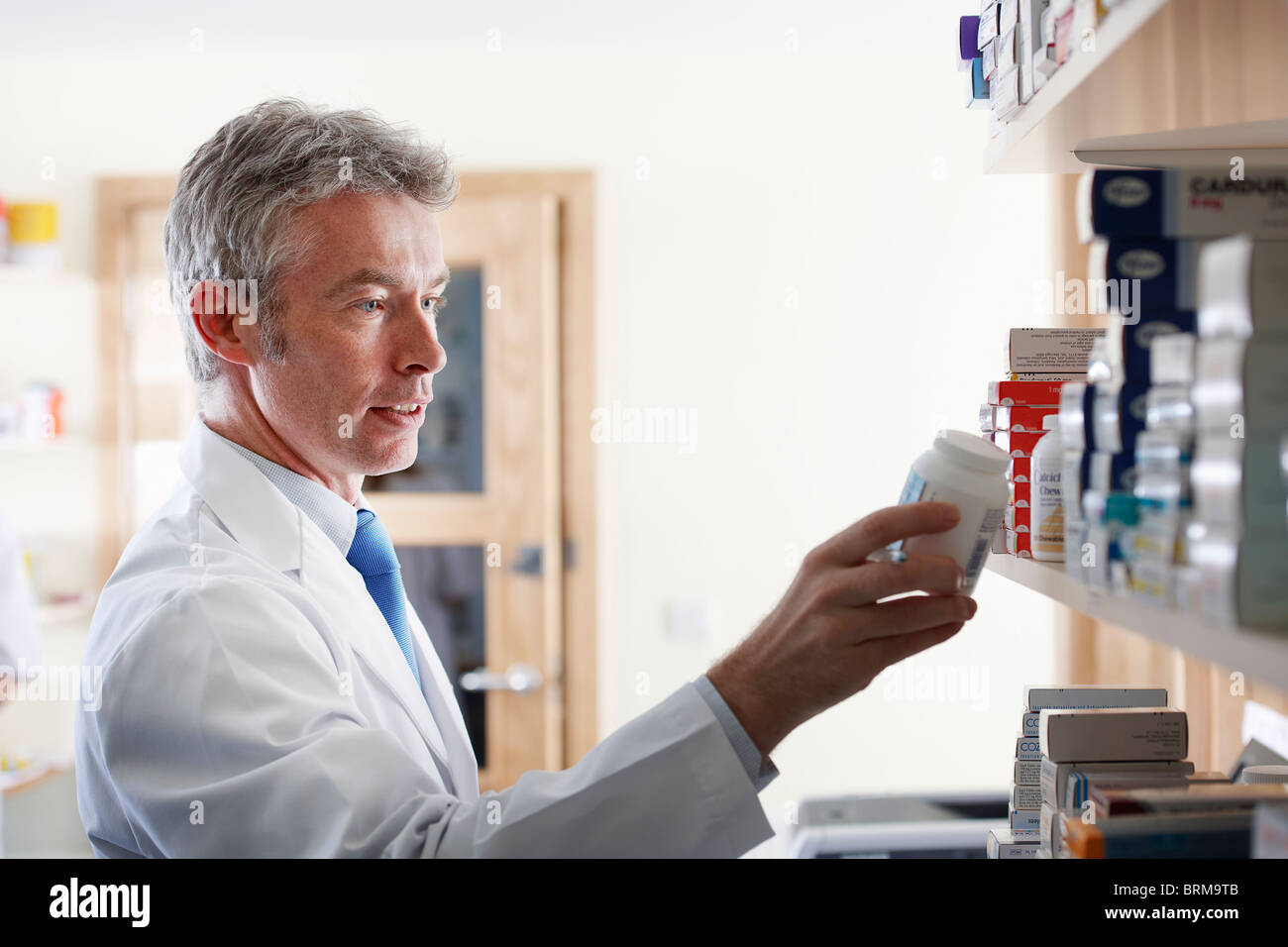 Pharmacist looking at pill bottle Stock Photo