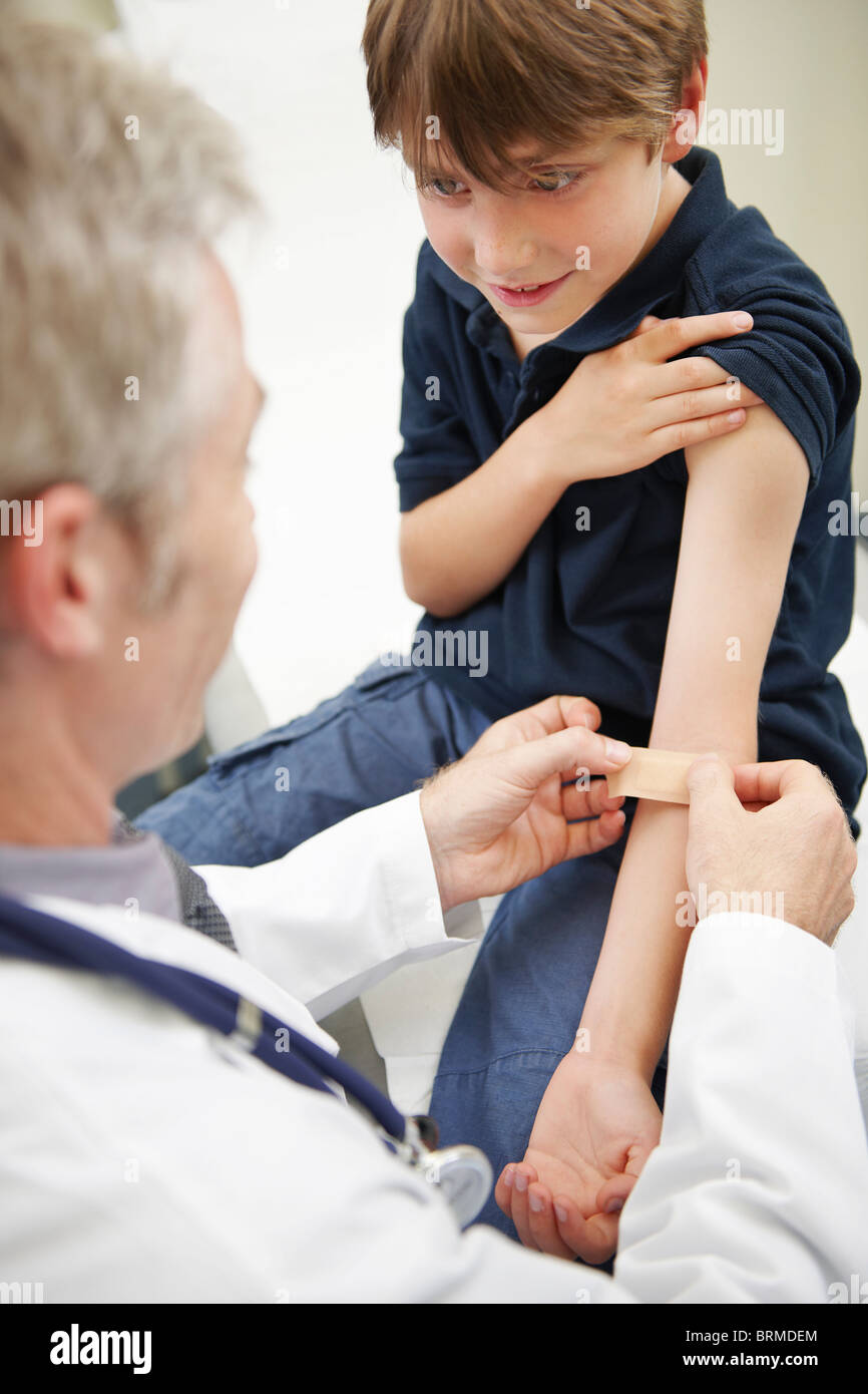 Doctor putting plaster on young boy Stock Photo