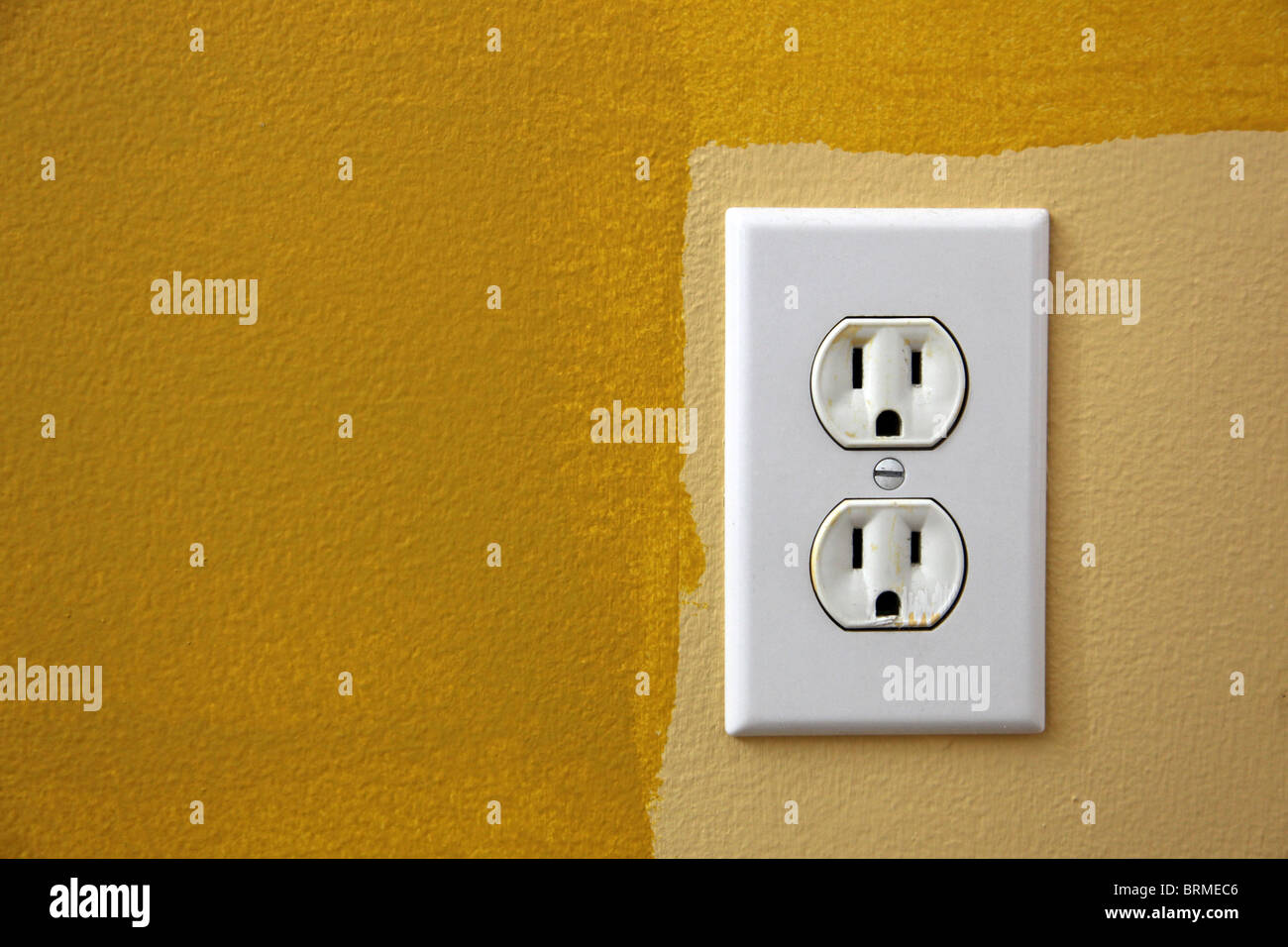 US plug in the wall with yellow paint around it. Stock Photo