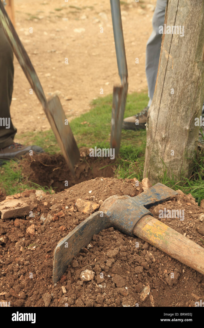 Two Volunteer Rangers work hard to dig a hole for a gate post on the