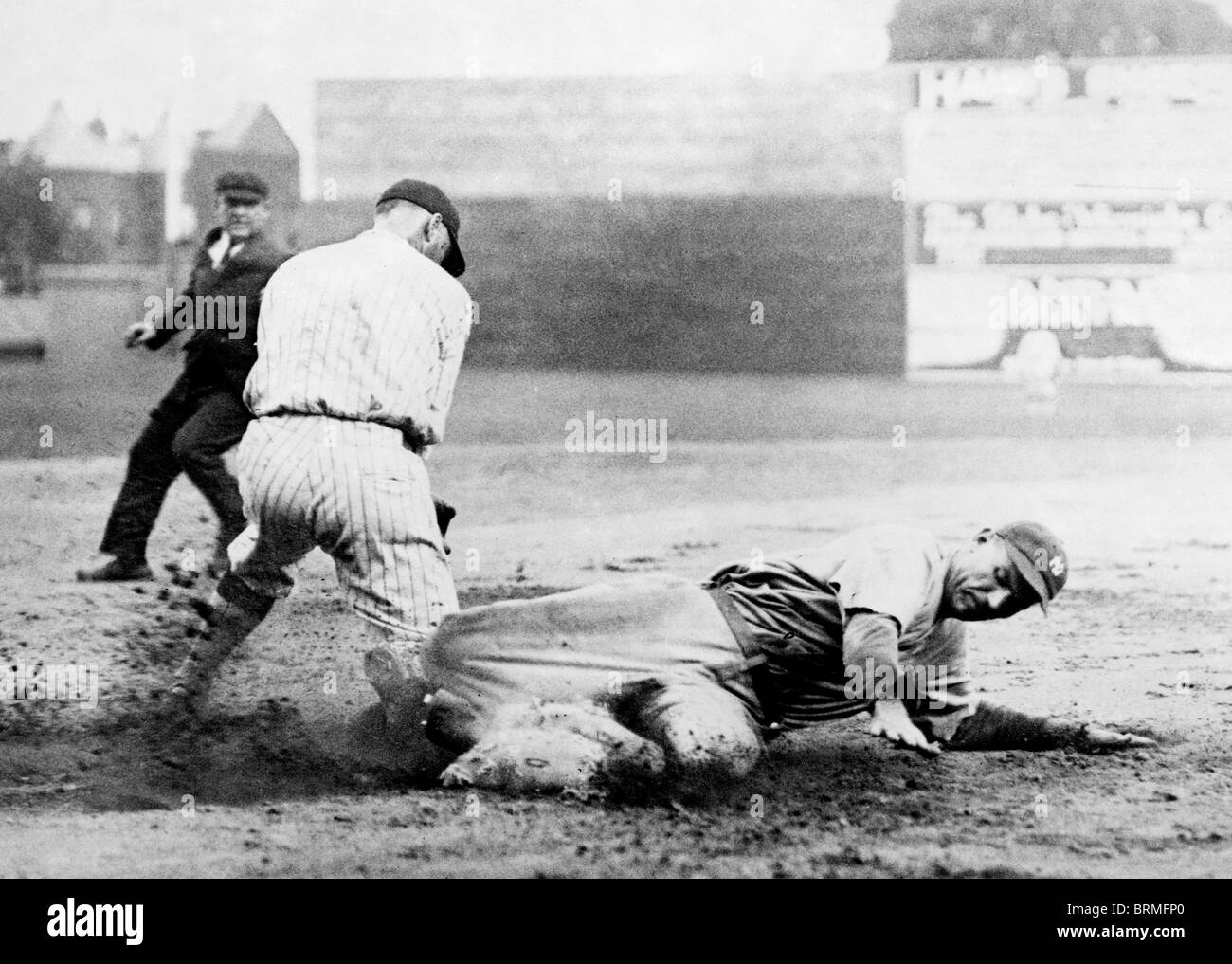 Umpire watches as New York Yankee player slides into base ahead of the tag during baseball game with Washington (circa 1920) Stock Photo
