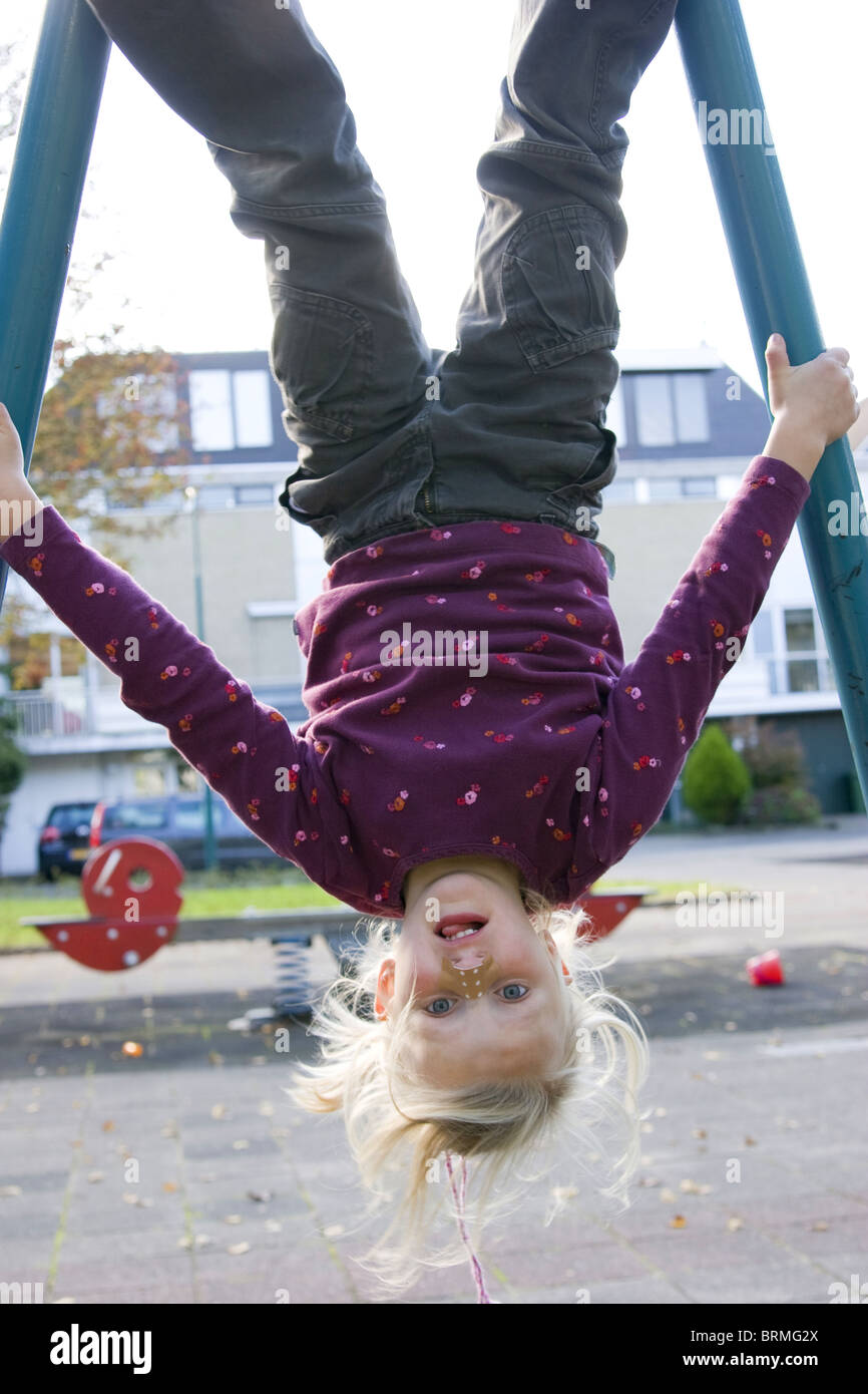 Child with blister on nose hanging upside-down in playground Stock Photo