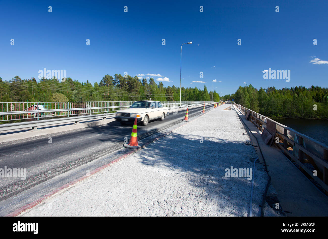 A car crossing a road bridge where half of the deck is under repair and asphalt has been stripped away , Finland Stock Photo