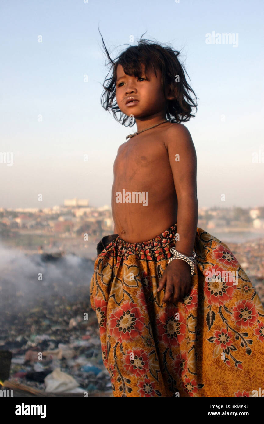 A young child laborer is staring at the sunset at The Stung Meanchey Landfill in Phnom Penh, Cambodia. Stock Photo