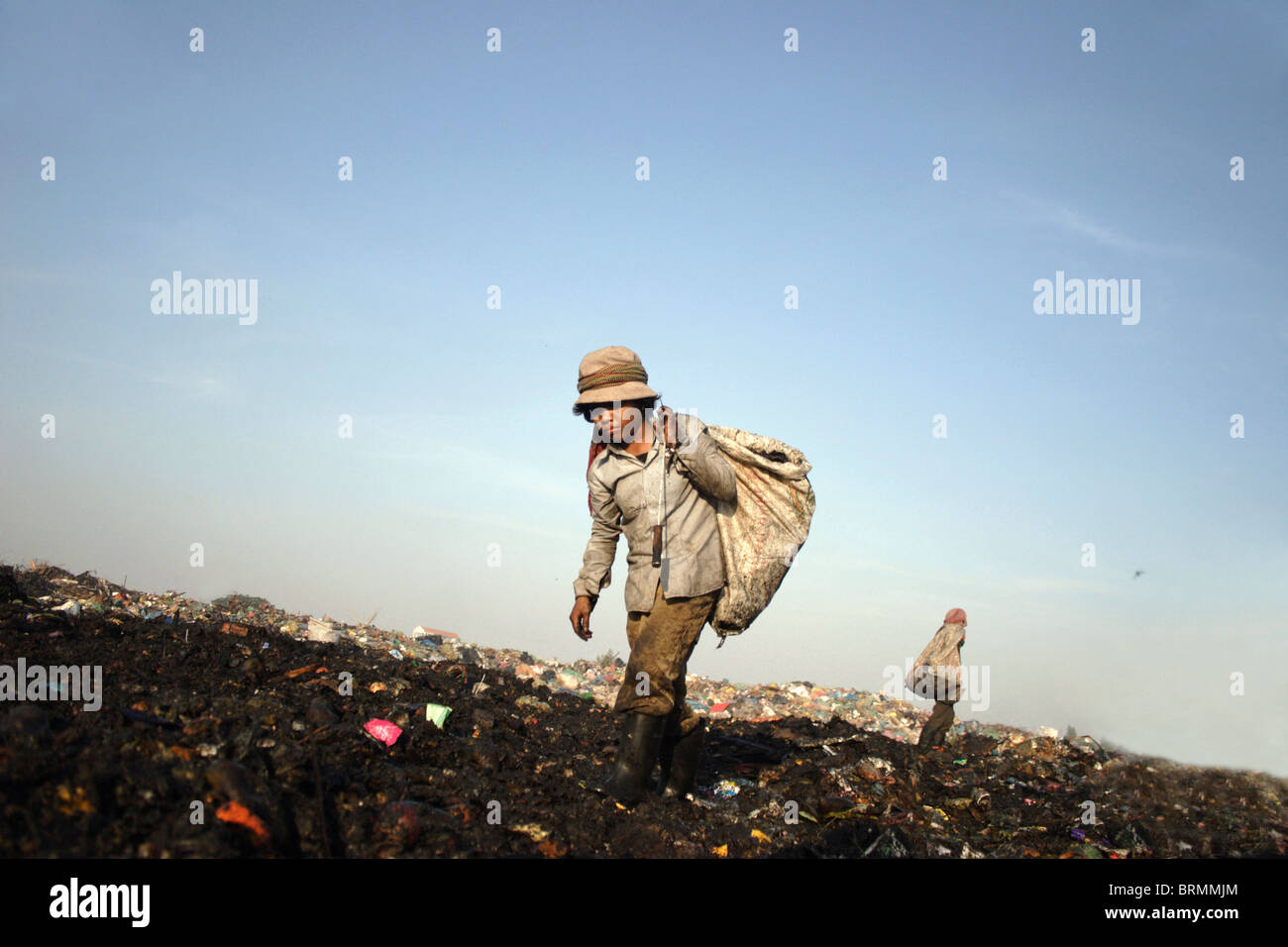 A child laborer carries a garbage bag while searching through garbage
