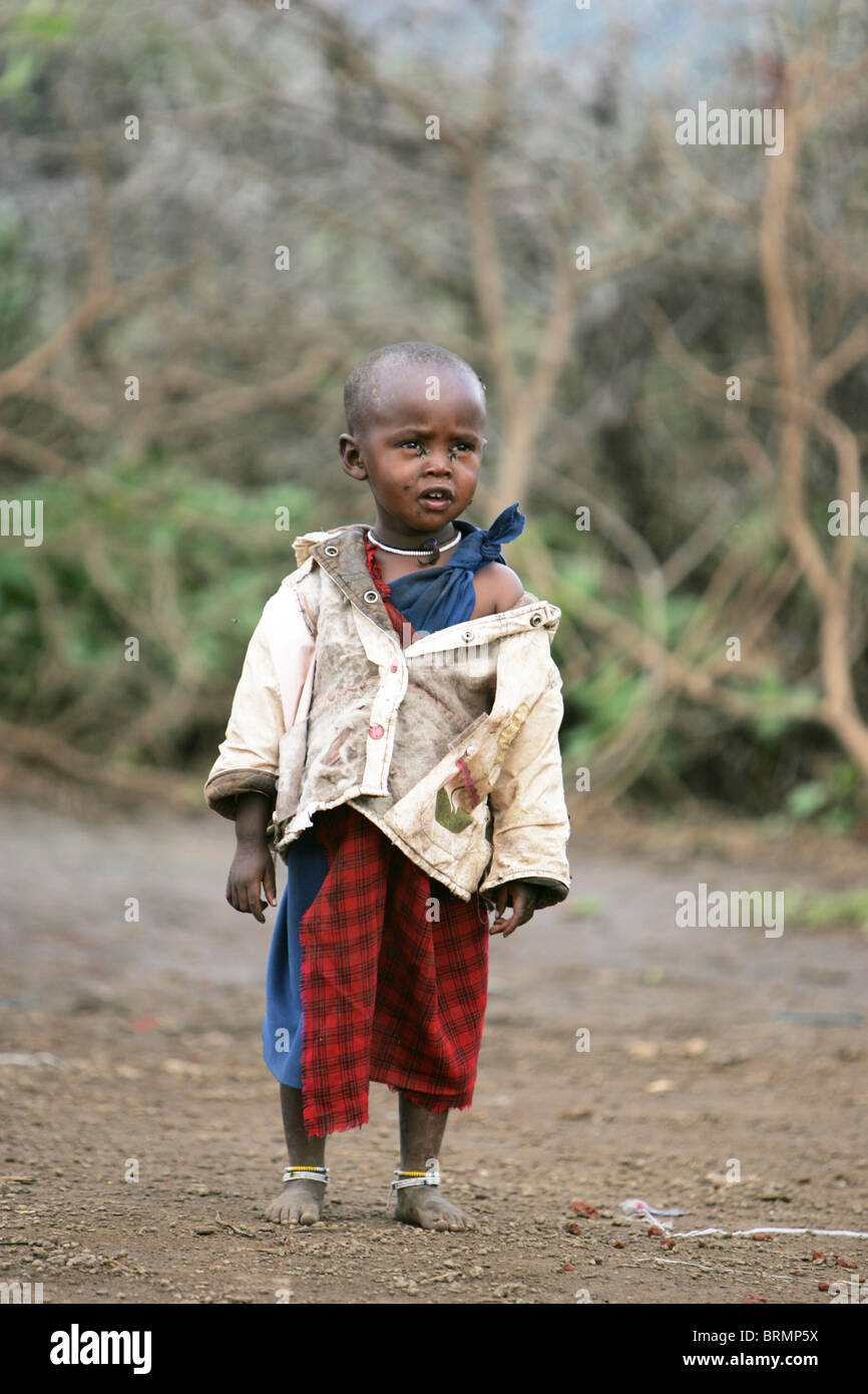 Maasai toddler aged about 2 year old standing dressed in a jacket and a traditional shuka Stock Photo